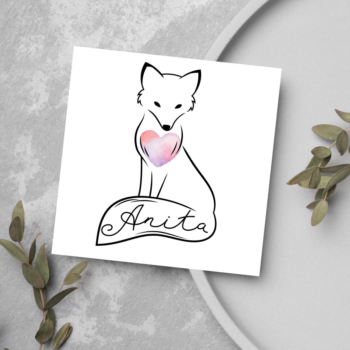 Square card with simple black line drawing of a fox sitting with its tail wrapped around its feet. It has a pink watercolour heart on its chest and personalised with a name on the tail in a calligraphy font
