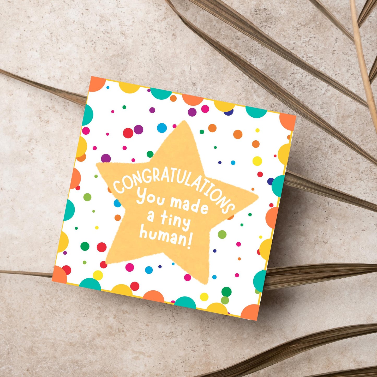Image of a square card, the card design is a multicoloured polka dot design with a large yellow coloured star in the middle and white text against the star that reads CONGRATULATIONS You made a tiny human!
