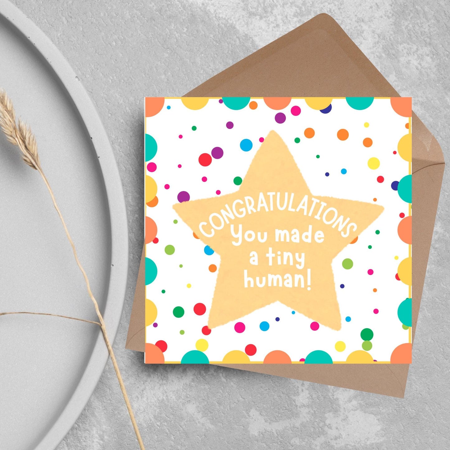 Image of a square card, the card design is a multicoloured polka dot design with a large yellow coloured star in the middle and white text against the star that reads CONGRATULATIONS You made a tiny human!