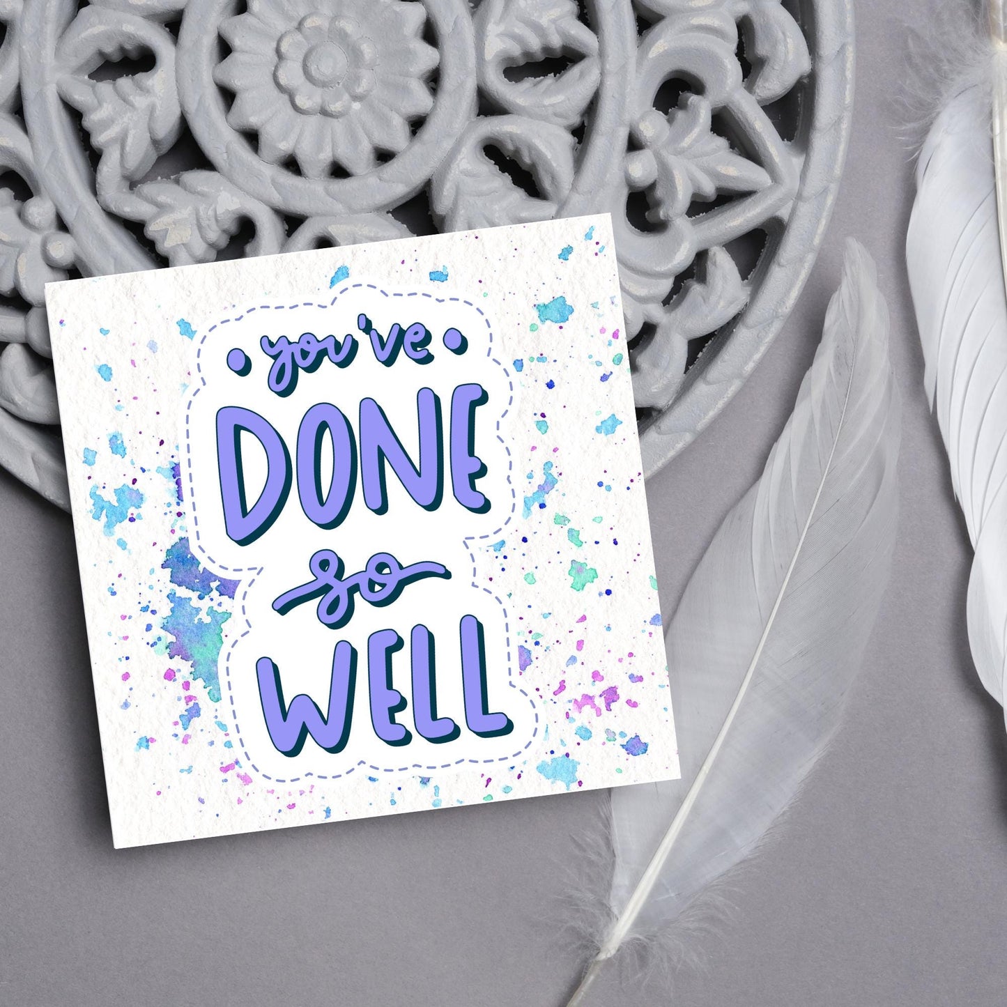 Square card with pastel colour paint splatter and white background. in the centre of the card is a sticker style image with you've done so well in a lilac cursive font