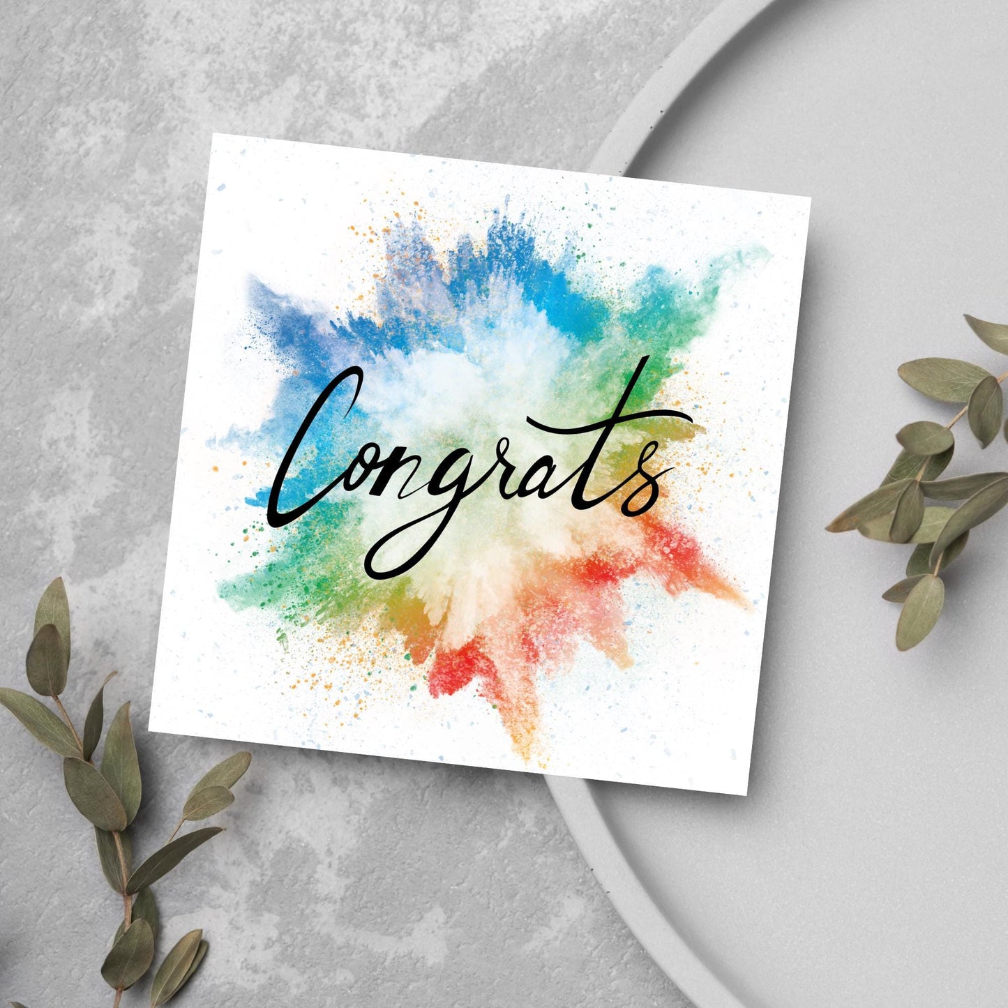 square card with rainbow paint splash against a white background. Black calligraphy style text overlay the paint with congrats