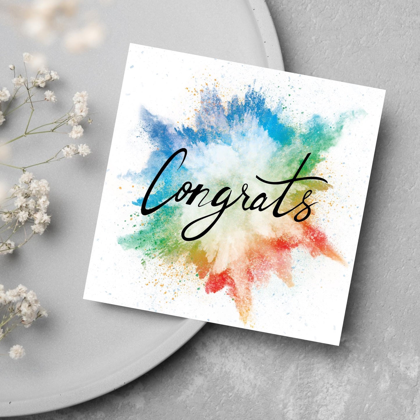 square card with rainbow paint splash against a white background. Black calligraphy style text overlay the paint with congrats