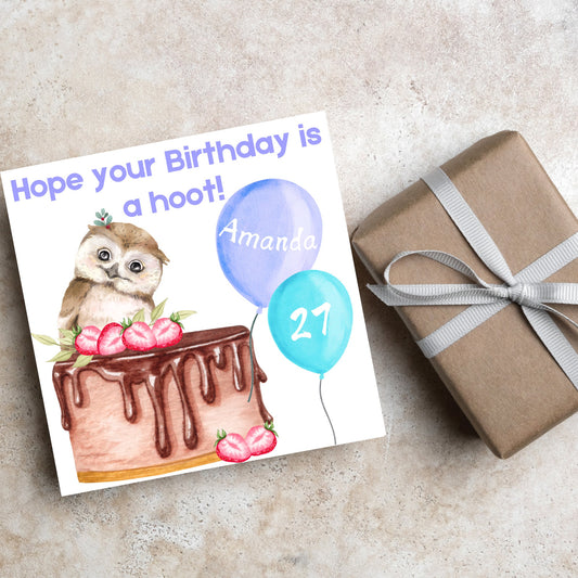 square birthday card with a cute owl sitting on a chocolate cake with the text hope our birthday is a hoot. next to the owl are two blue balloons, one with the name of the person and one with the age in white writing
