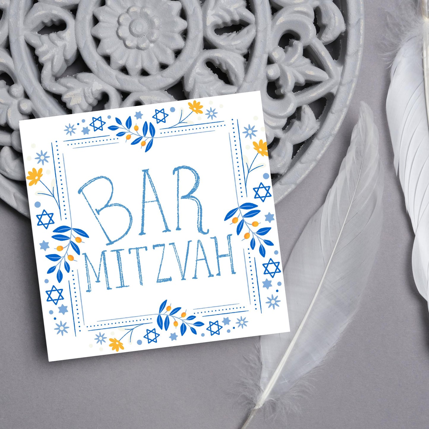 square bar mitzvah card with a sketchy drawn bar mitzvah in the centre in a soft blue, with a decorative frame featuring flowers and stars of david in blues and yellows
