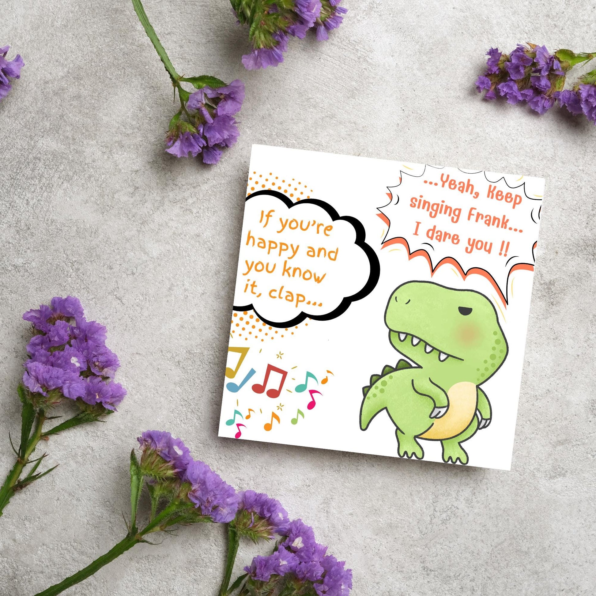 A cute, grumpy green T-Rex with tiny arms is featured. Text reads, "If you're happy and you know it, clap..." The T-Rex responds, "...Yeah, keep singing Frank... I dare you!!" Musical notes add a playful touch.