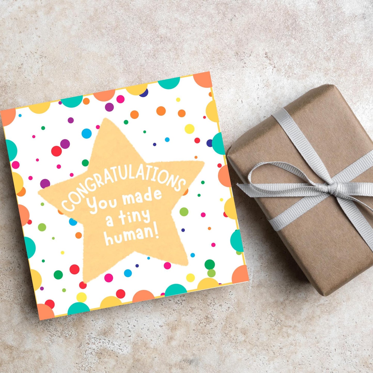Image of a square card, the card design is a multicoloured polka dot design with a large yellow coloured star in the middle and white text against the star that reads CONGRATULATIONS You made a tiny human!