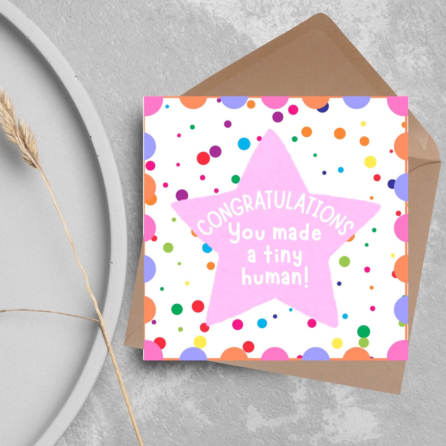 Image of a square card, the card design is a multicoloured polka dot design with a large pink coloured star in the middle and white text against the star that reads CONGRATULATIONS You made a tiny human!