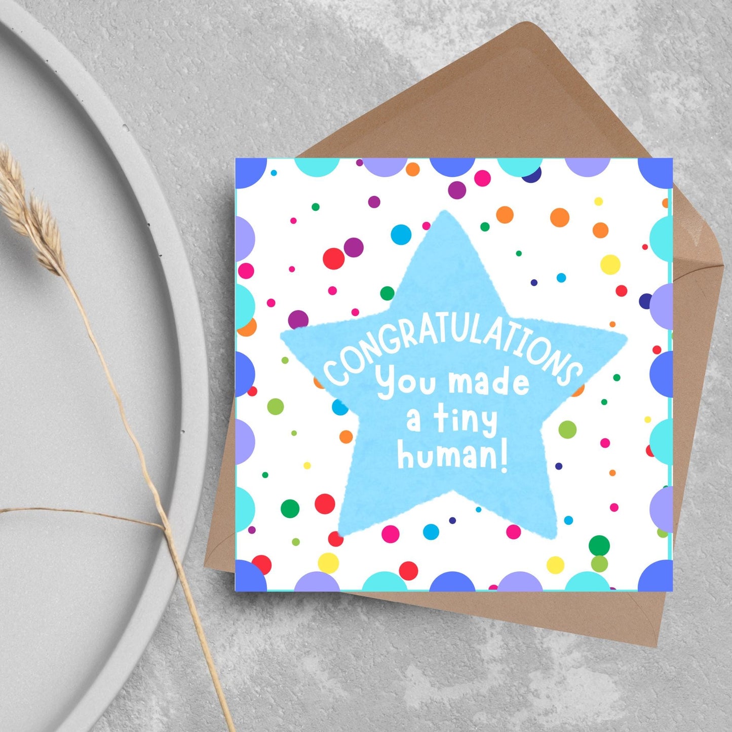 Image of a square card, the card design is a multicoloured polka dot design with a large blue coloured star in the middle and white text against the star that reads CONGRATULATIONS You made a tiny human!