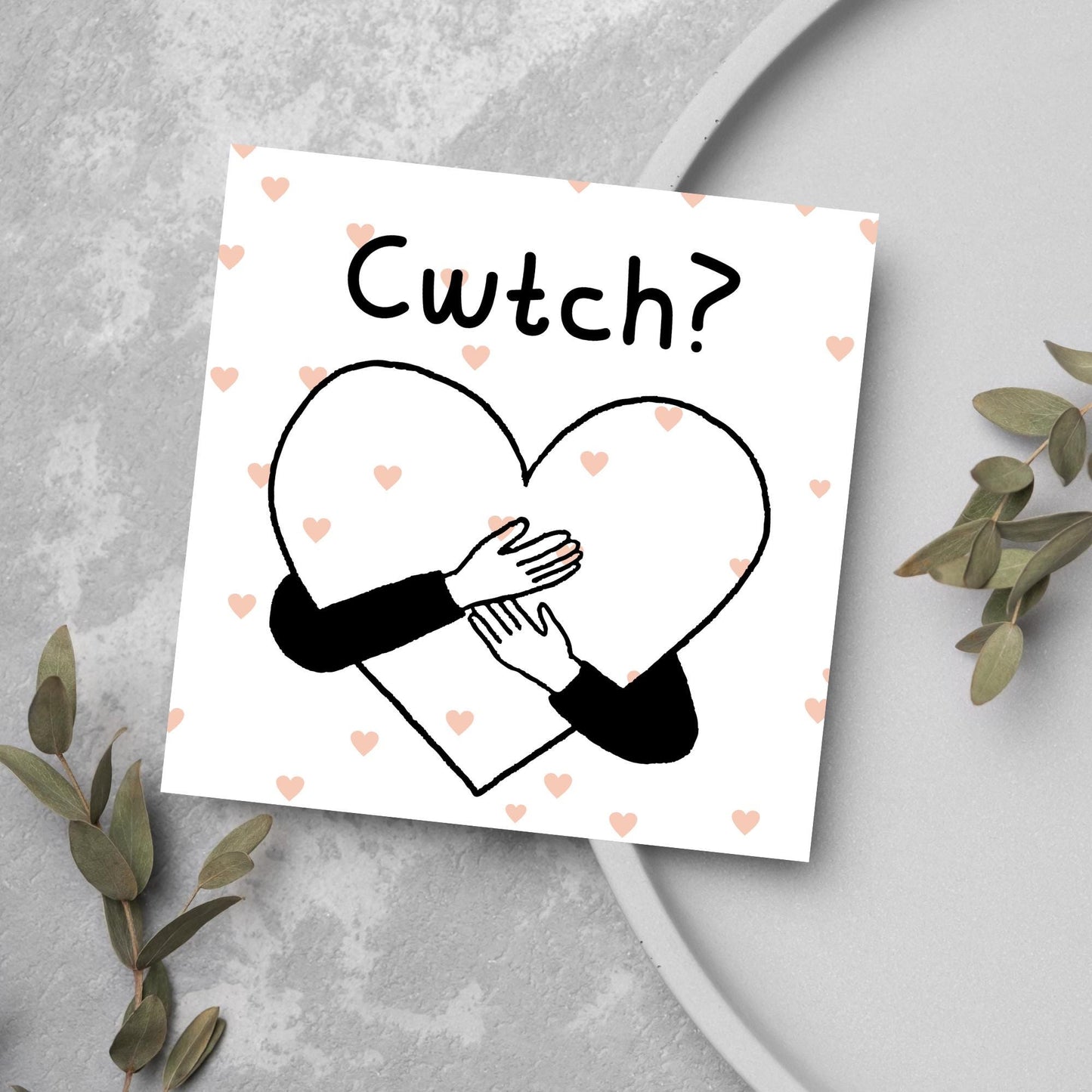 Square Greeting card small with subtle pink hearts in the background of a line drawn heart with hands hugging it and the word CWTCH? above it in handwritten style text