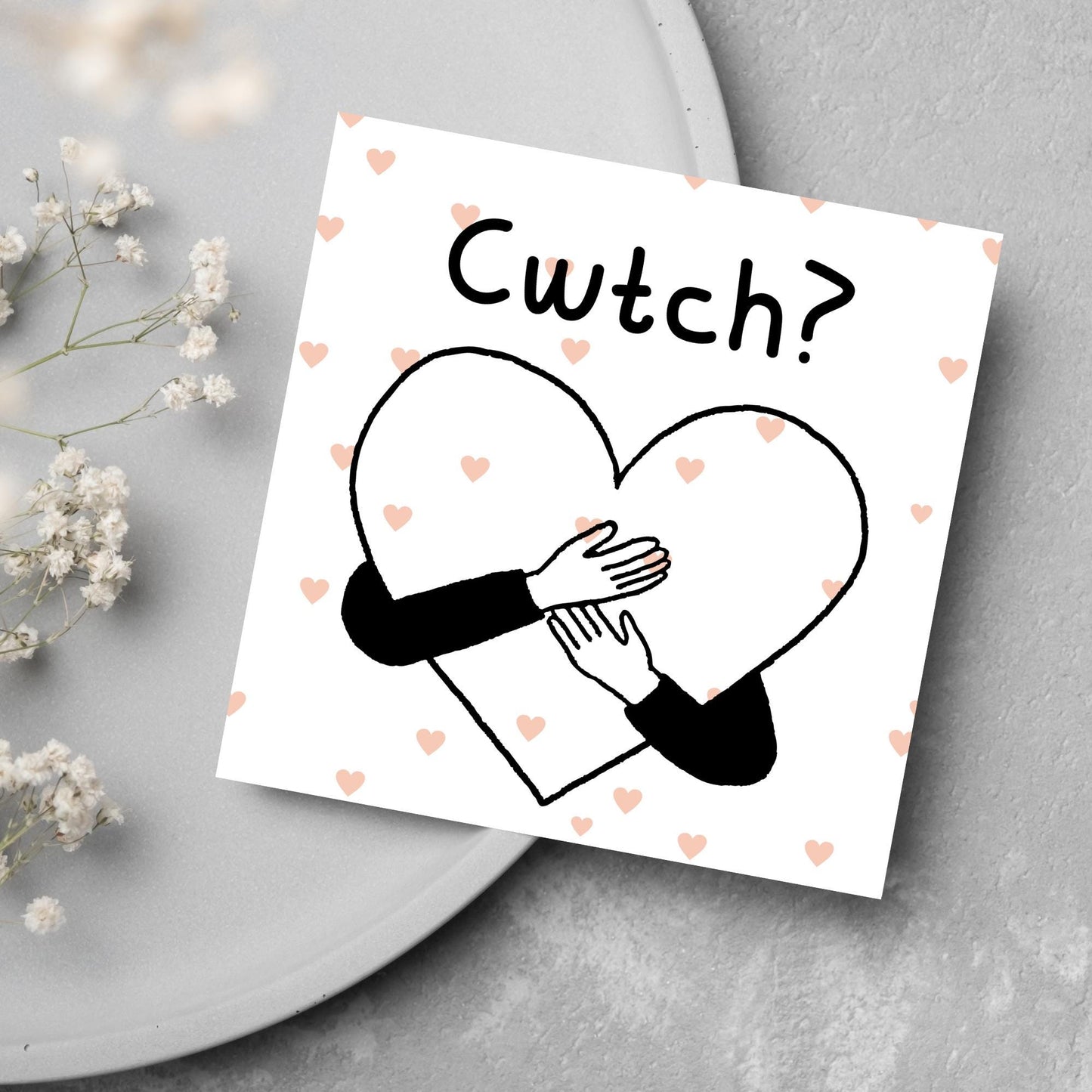 Square Greeting card small with subtle pink hearts in the background of a line drawn heart with hands hugging it and the word CWTCH? above it in handwritten style text