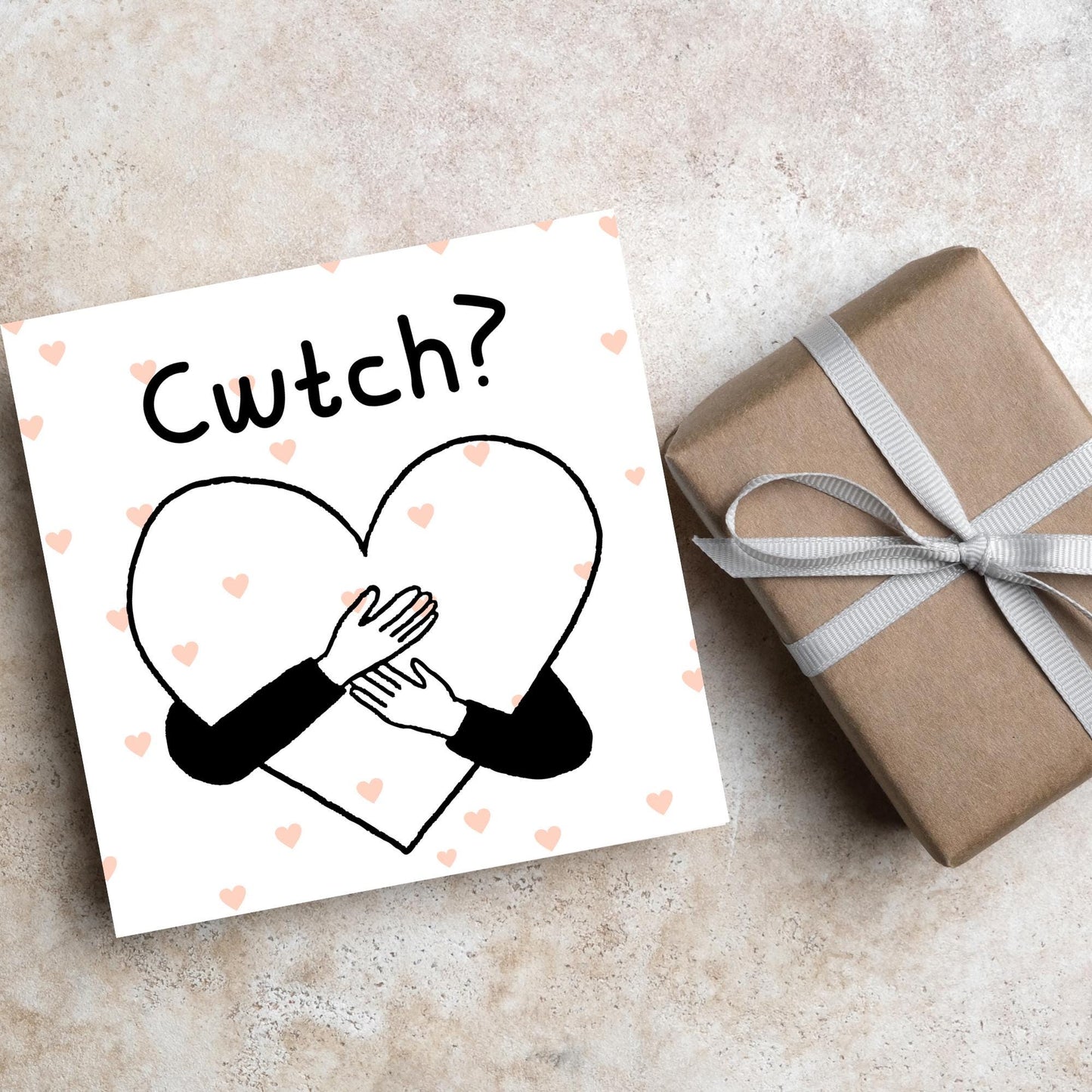 Square Greeting card small with subtle pink hearts in the background of a line drawn heart with hands hugging it and the word CWTCH? above it in handwritten style text