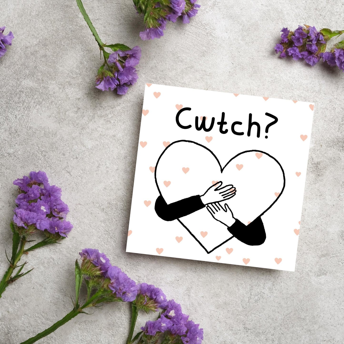 Square Greeting card small with subtle pink hearts in the background of a line drawn heart with hands hugging it and the word CWTCH? above it in handwritten style text