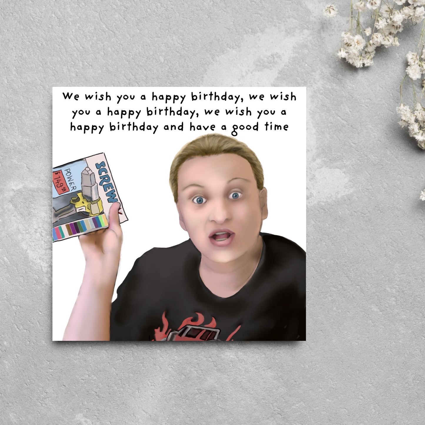 Square birthday card with a hand drawn image of Kerry from this country looking shocked and holding up a screwfix catalogue with the text we wish you a happy birthday, we wish you a happy birthday, we wish you a happy birthday and have a good time