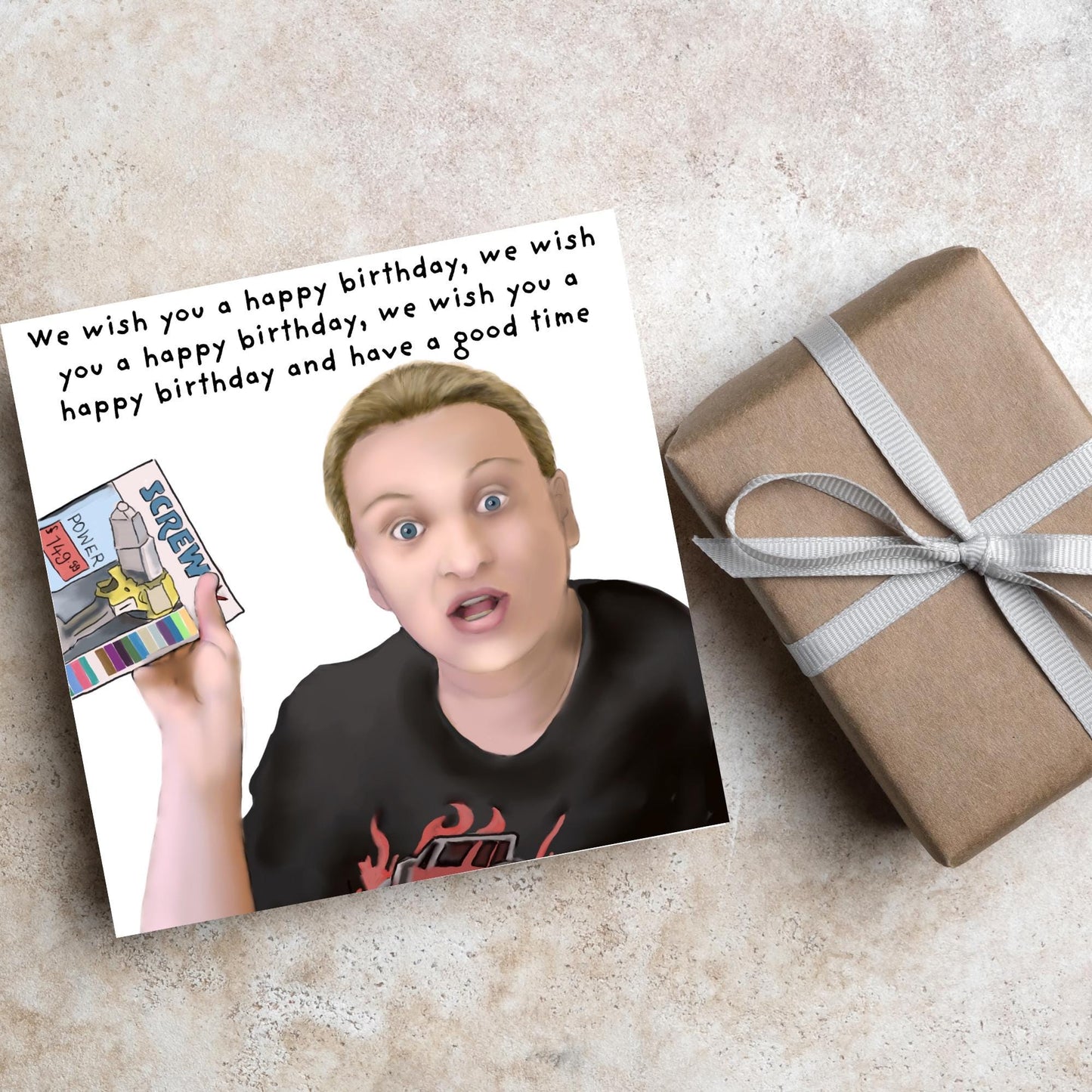 Square birthday card with a hand drawn image of Kerry from this country looking shocked and holding up a screwfix catalogue with the text we wish you a happy birthday, we wish you a happy birthday, we wish you a happy birthday and have a good time