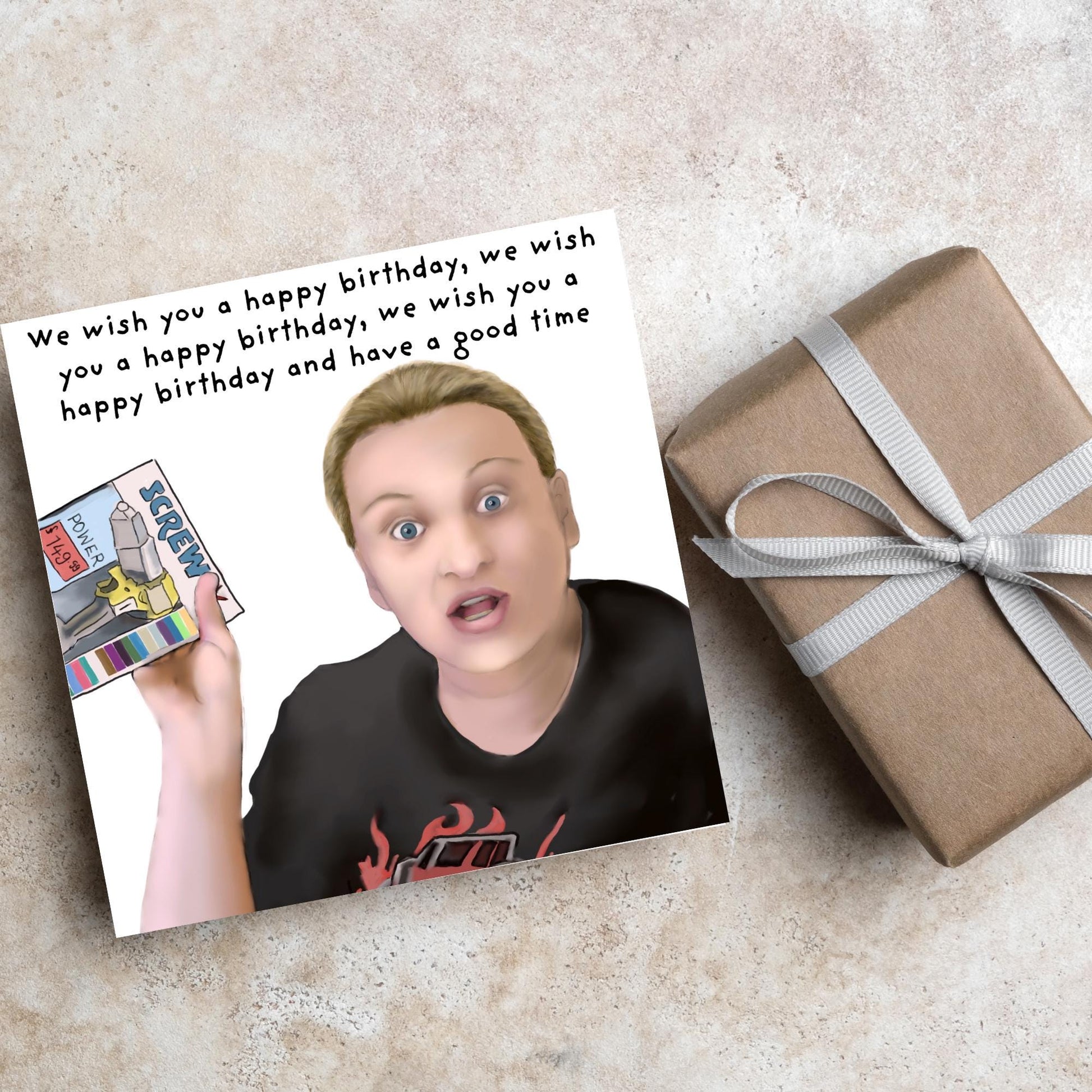 Square birthday card with a hand drawn image of Kerry from this country looking shocked and holding up a screwfix catalogue with the text we wish you a happy birthday, we wish you a happy birthday, we wish you a happy birthday and have a good time