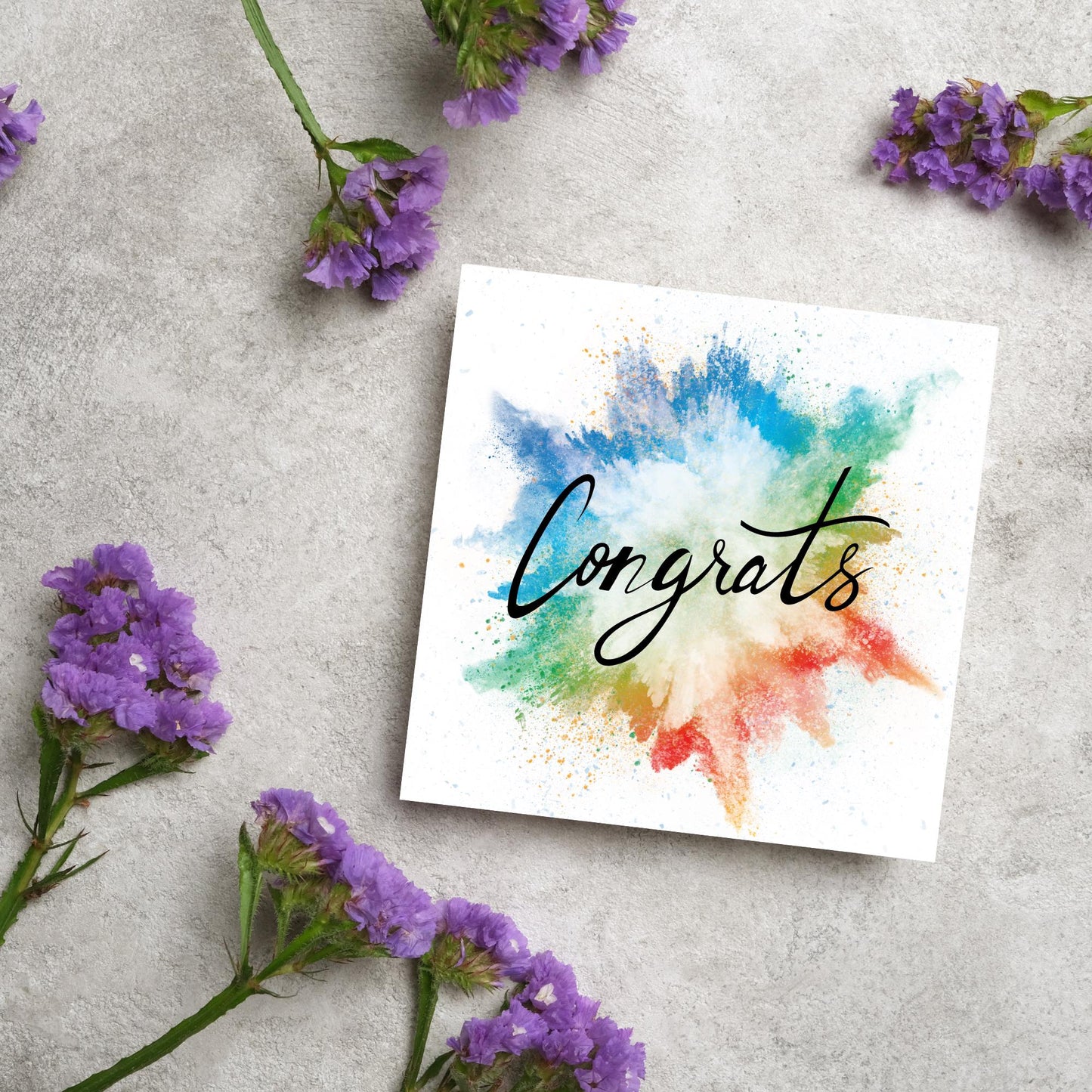 square card with rainbow paint splash against a white background. Black calligraphy style text overlay the paint with congrats