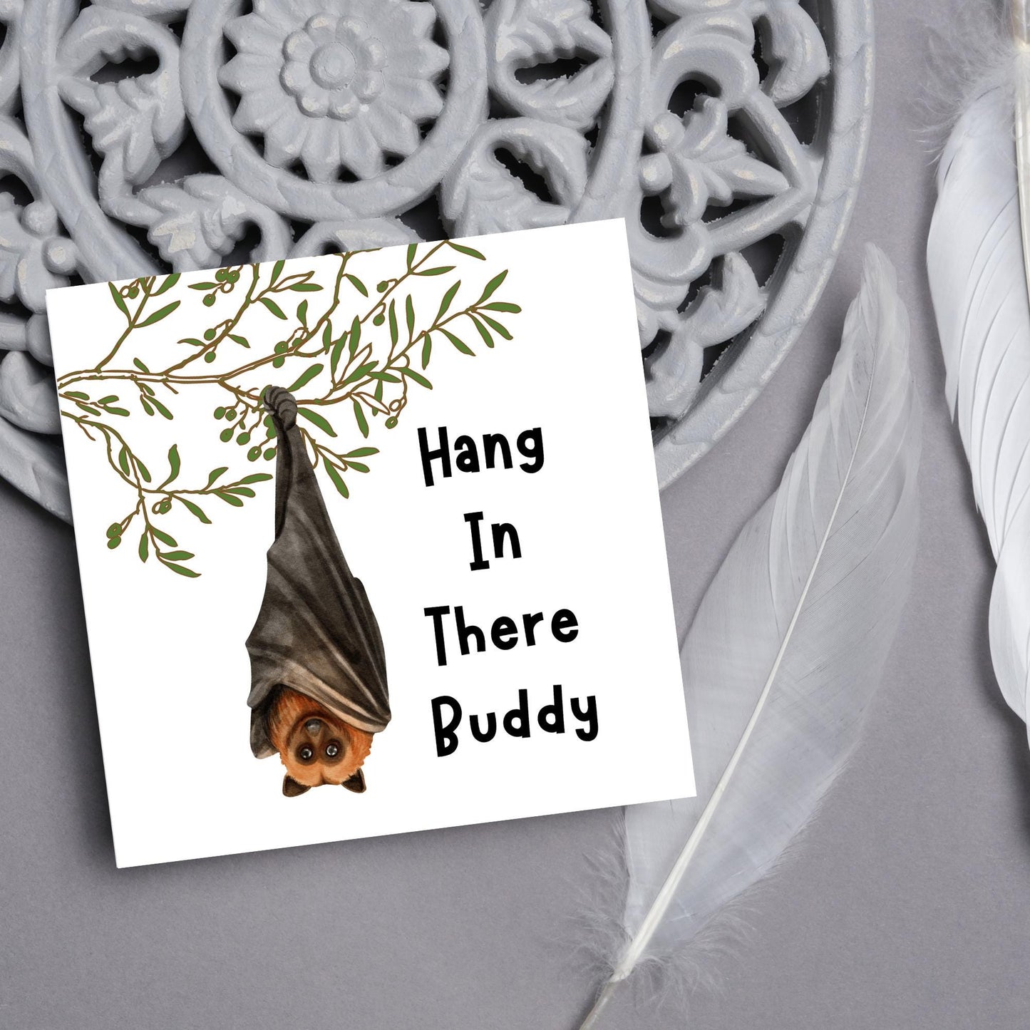 square card with an illustration of a bat hanging upside down from a tree branch with black text next to it that reads - Hang in there buddy