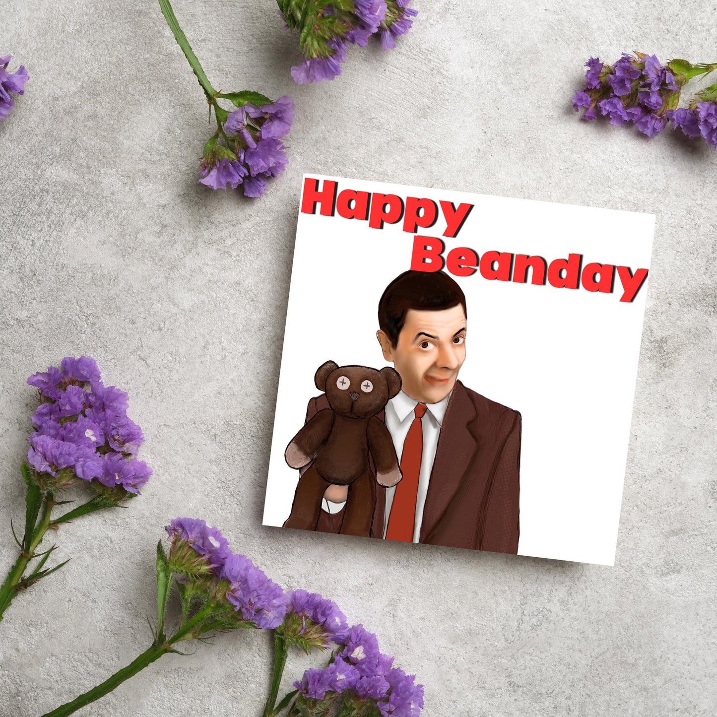 square card with a hand drawn image of Mr bean holding his teddy pooky with a cheeky smile on his face with the words Happy Beanday above in bold red text