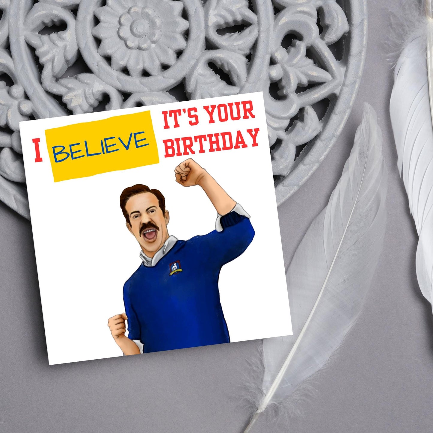 square greetings card with a hand drawn image of Jason Sudeikis character Ted Lasso giving a fist pump with the text - I believe it's your birthday