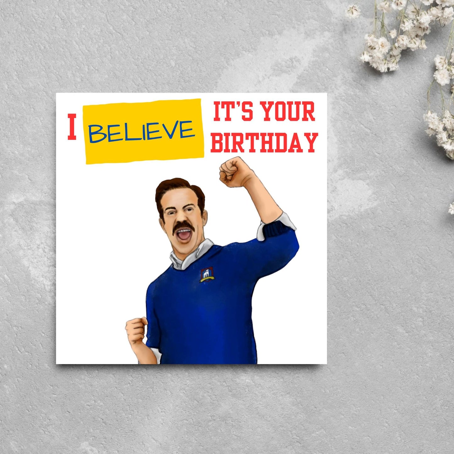 square greetings card with a hand drawn image of Jason Sudeikis character Ted Lasso giving a fist pump with the text - I believe it's your birthday