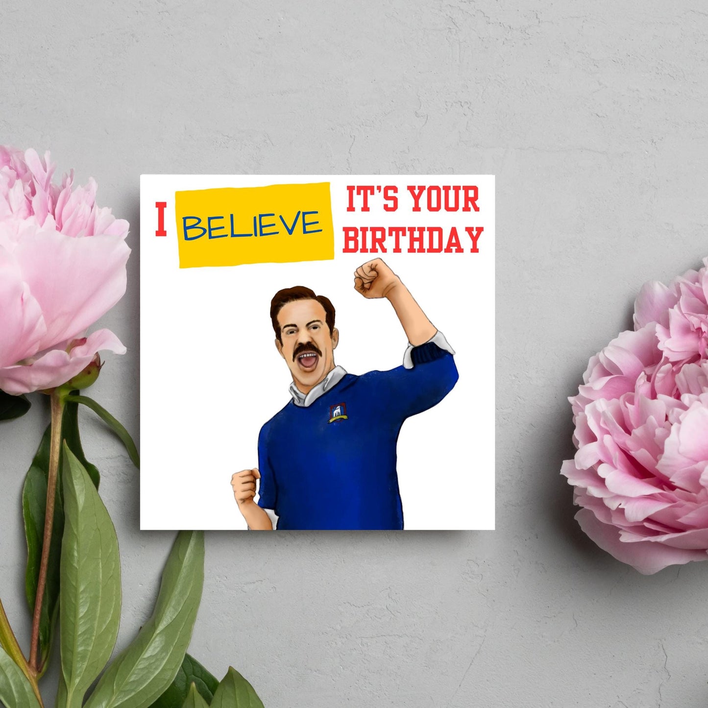 square greetings card with a hand drawn image of Jason Sudeikis character Ted Lasso giving a fist pump with the text - I believe it's your birthday