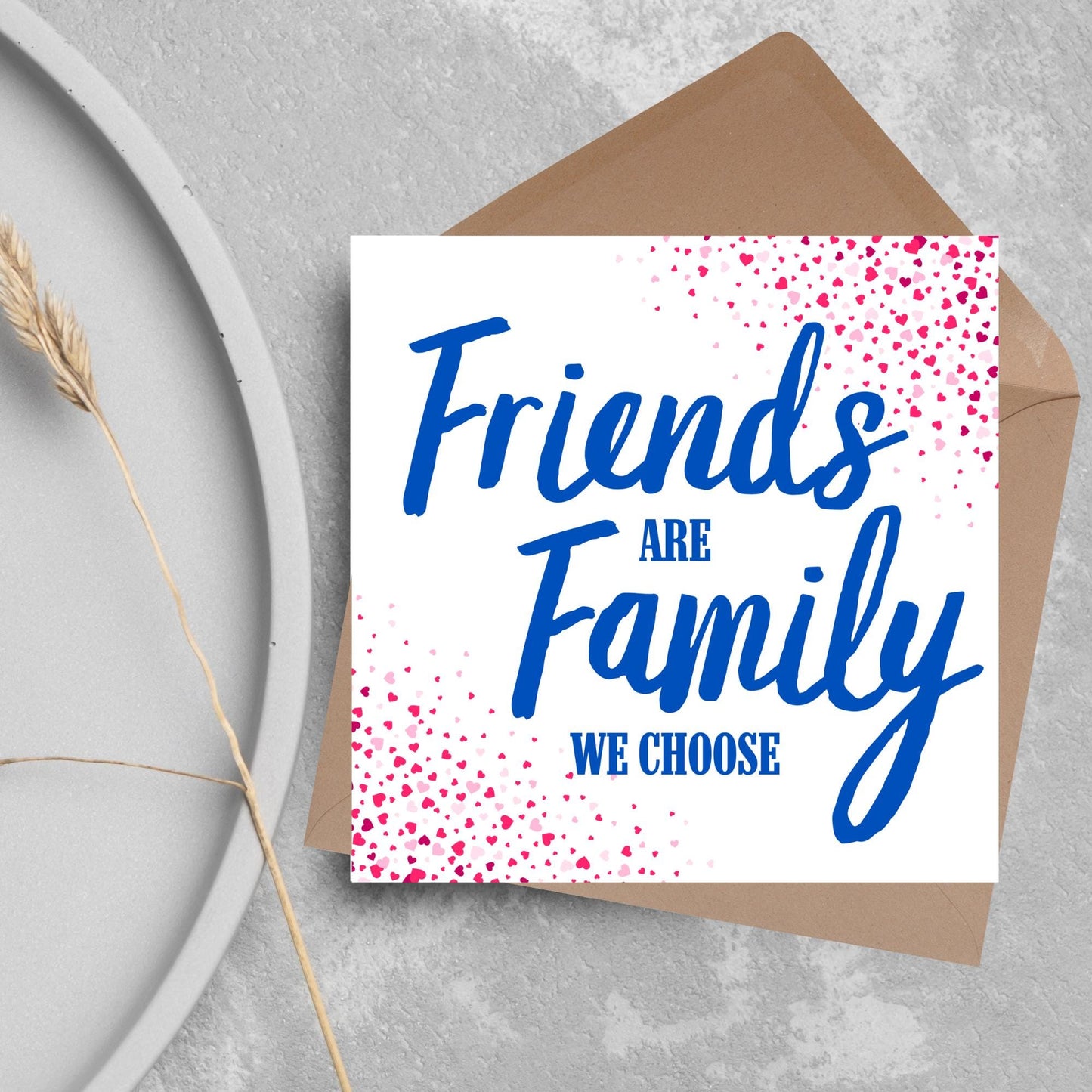 Square card with small hearts on opposite corners in shades of pink and blue writing in the centre that reads Friends are Family we choose