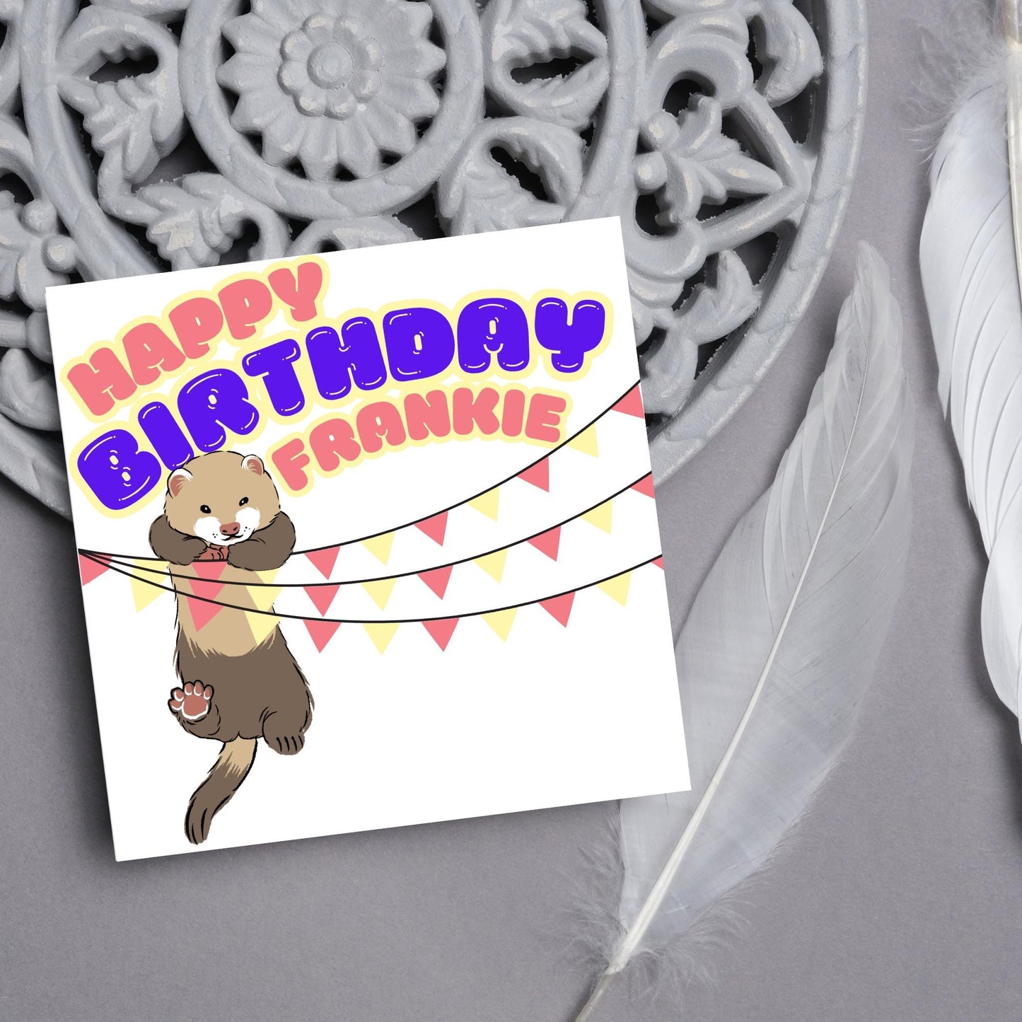 square card with an image of a ferret hanging off pink and yellow bunting with bold pink and purple text above that reads happy birthday frankie in a bubble font