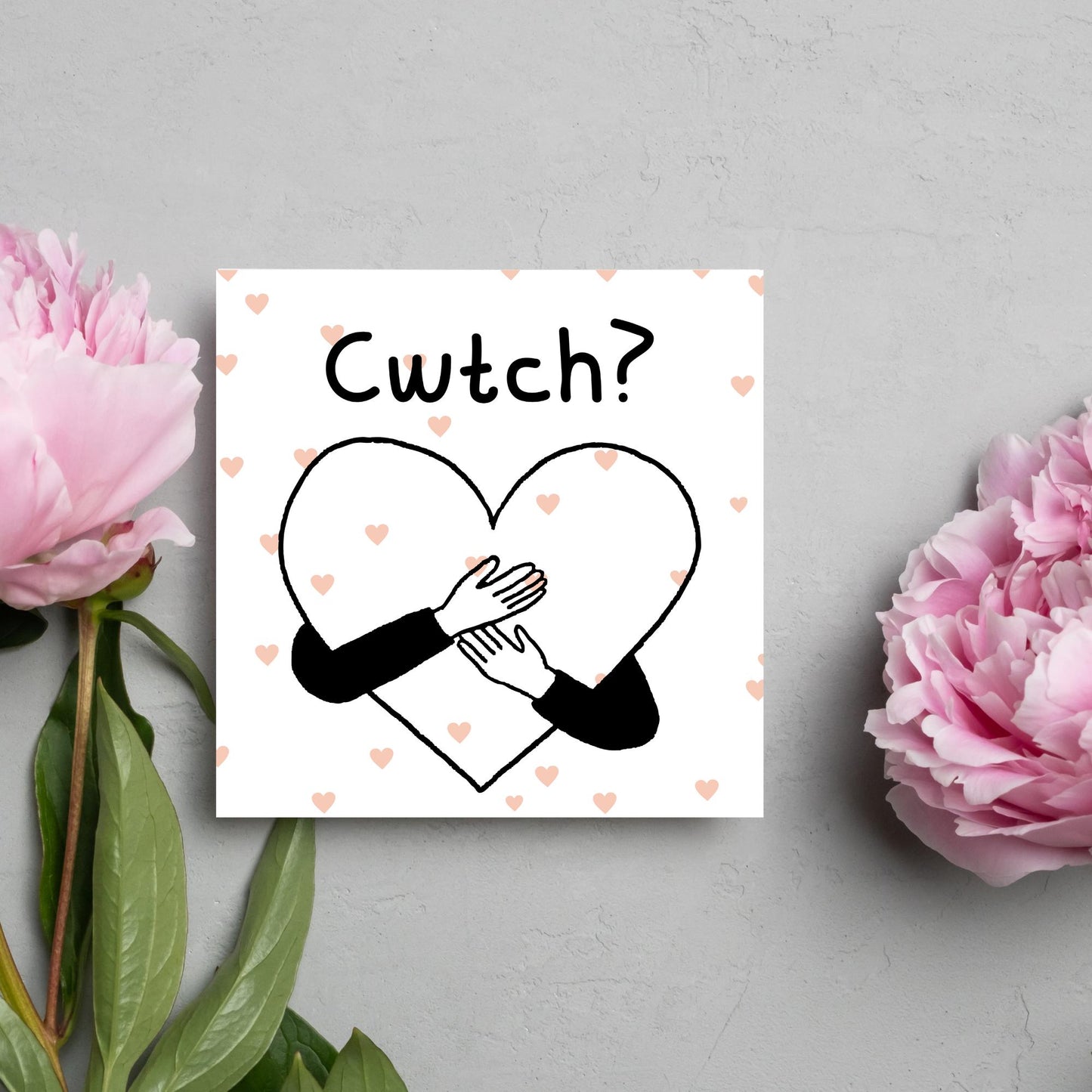 Square Greeting card small with subtle pink hearts in the background of a line drawn heart with hands hugging it and the word CWTCH? above it in handwritten style text