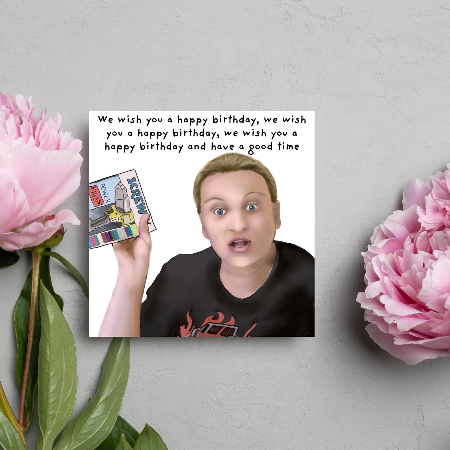 Square birthday card with a hand drawn image of Kerry from this country looking shocked and holding up a screwfix catalogue with the text we wish you a happy birthday, we wish you a happy birthday, we wish you a happy birthday and have a good time