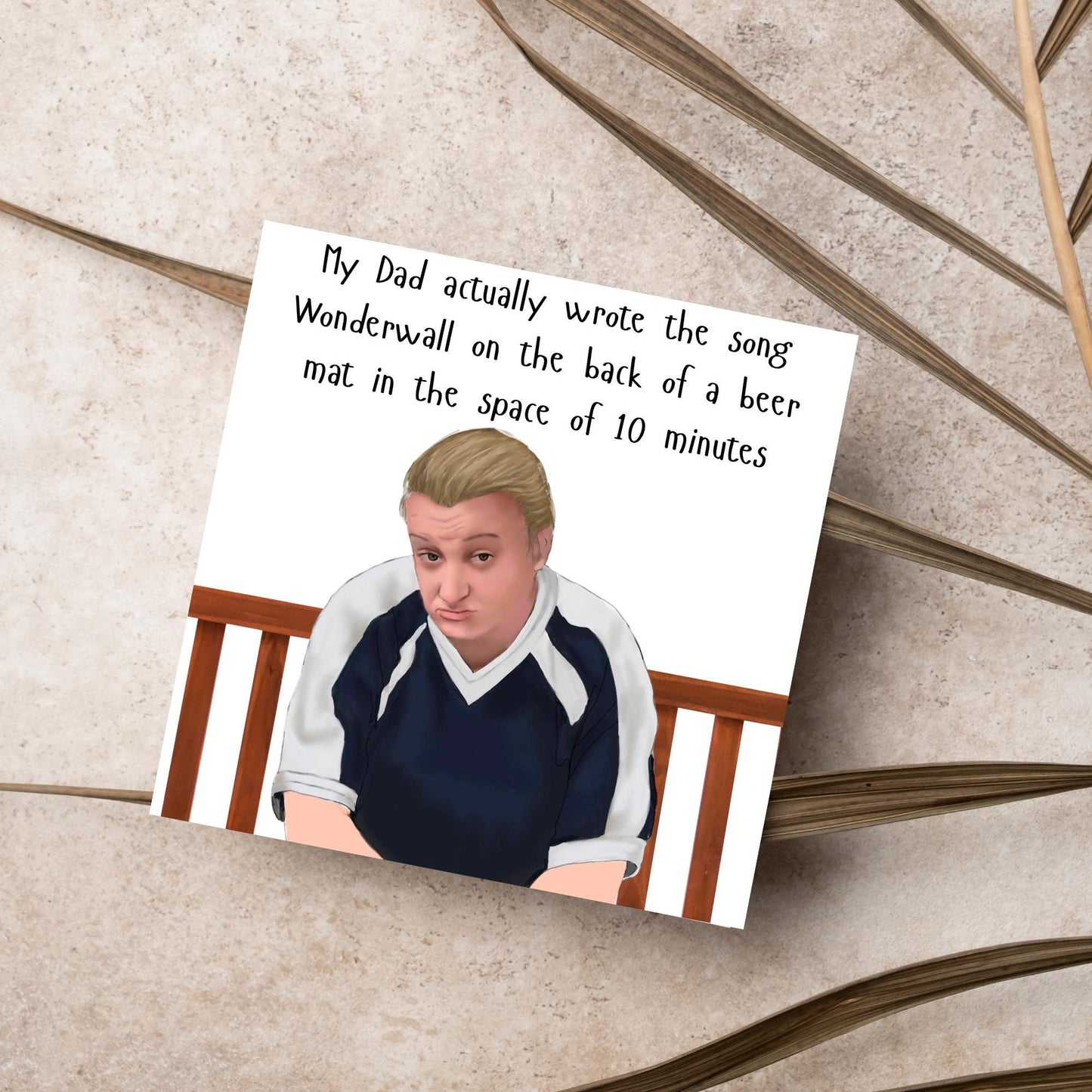 square card with a hand drawn image of kerry from this country sitting on a bench with handwritten style text above - My Dad actually wrote the song Wonderwall on the back of a beer mat in the space of 10 minutes