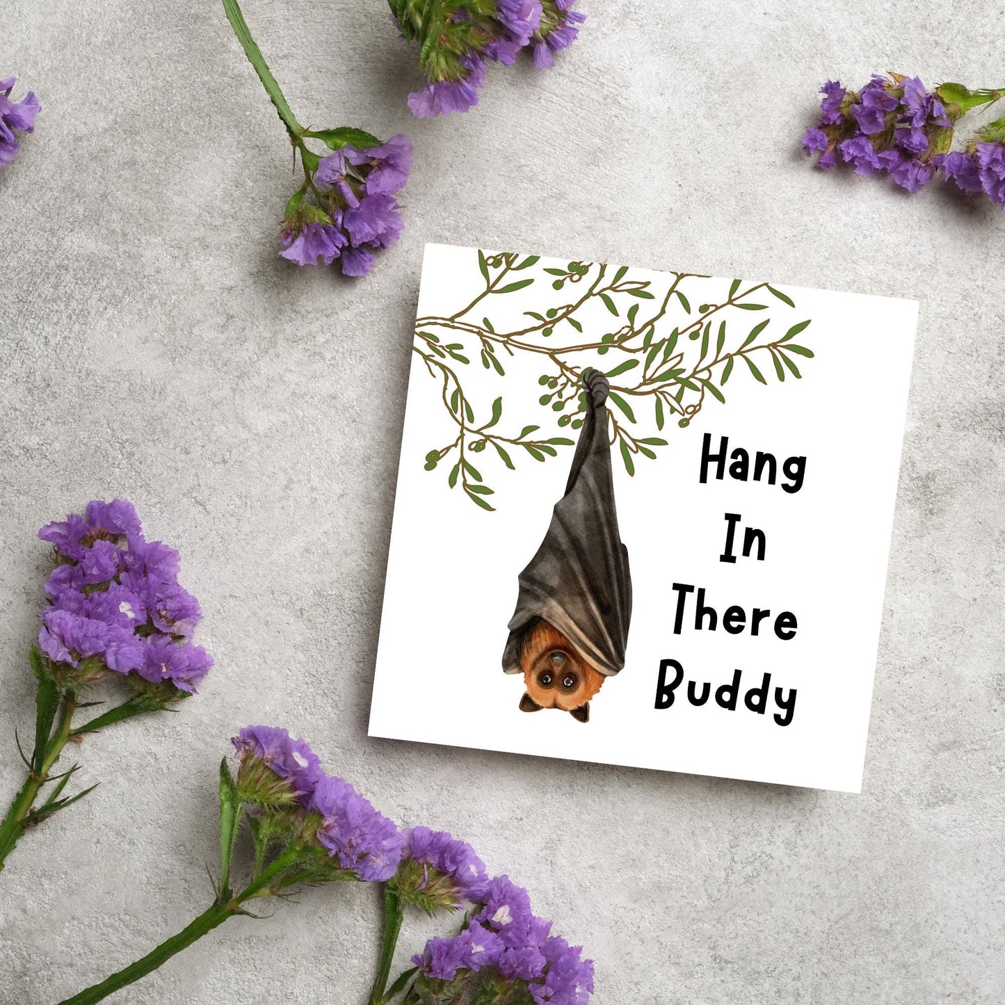 square card with an illustration of a bat hanging upside down from a tree branch with black text next to it that reads - Hang in there buddy