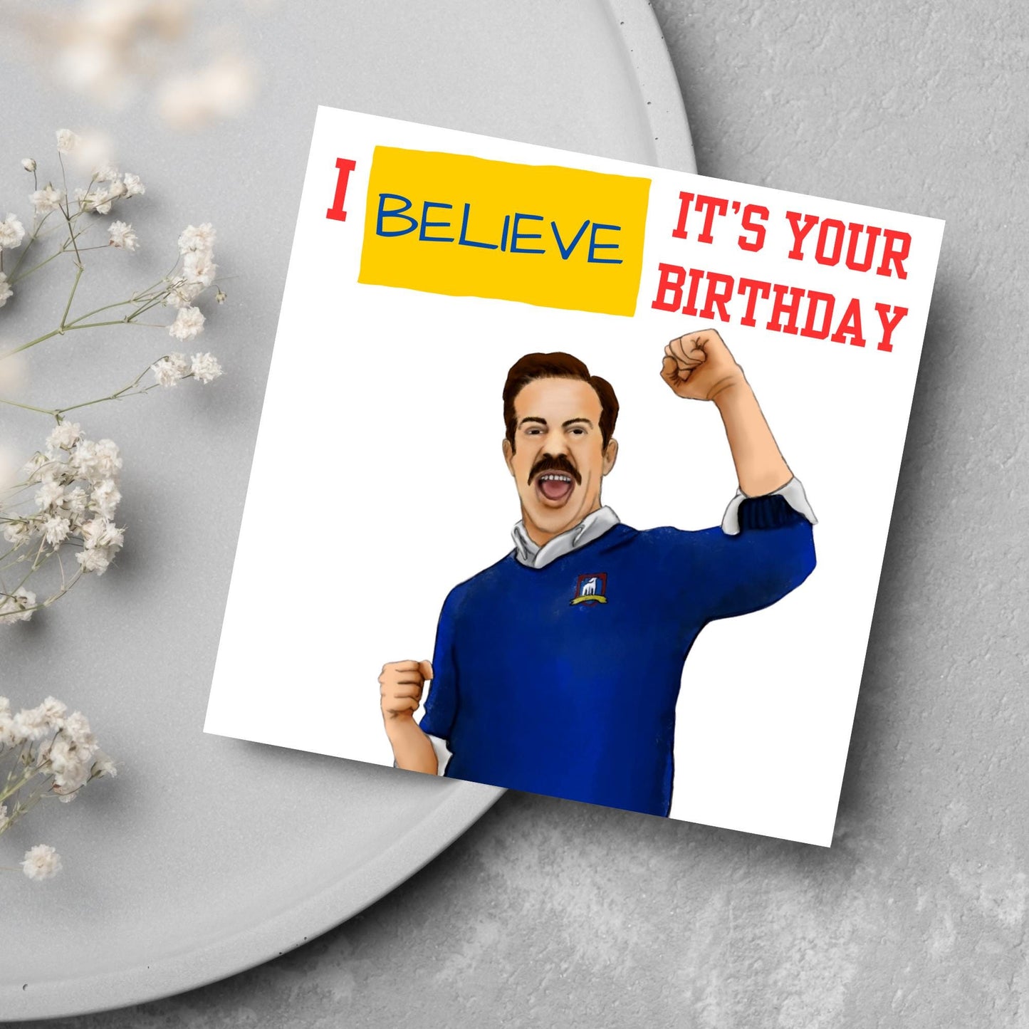 square greetings card with a hand drawn image of Jason Sudeikis character Ted Lasso giving a fist pump with the text - I believe it's your birthday
