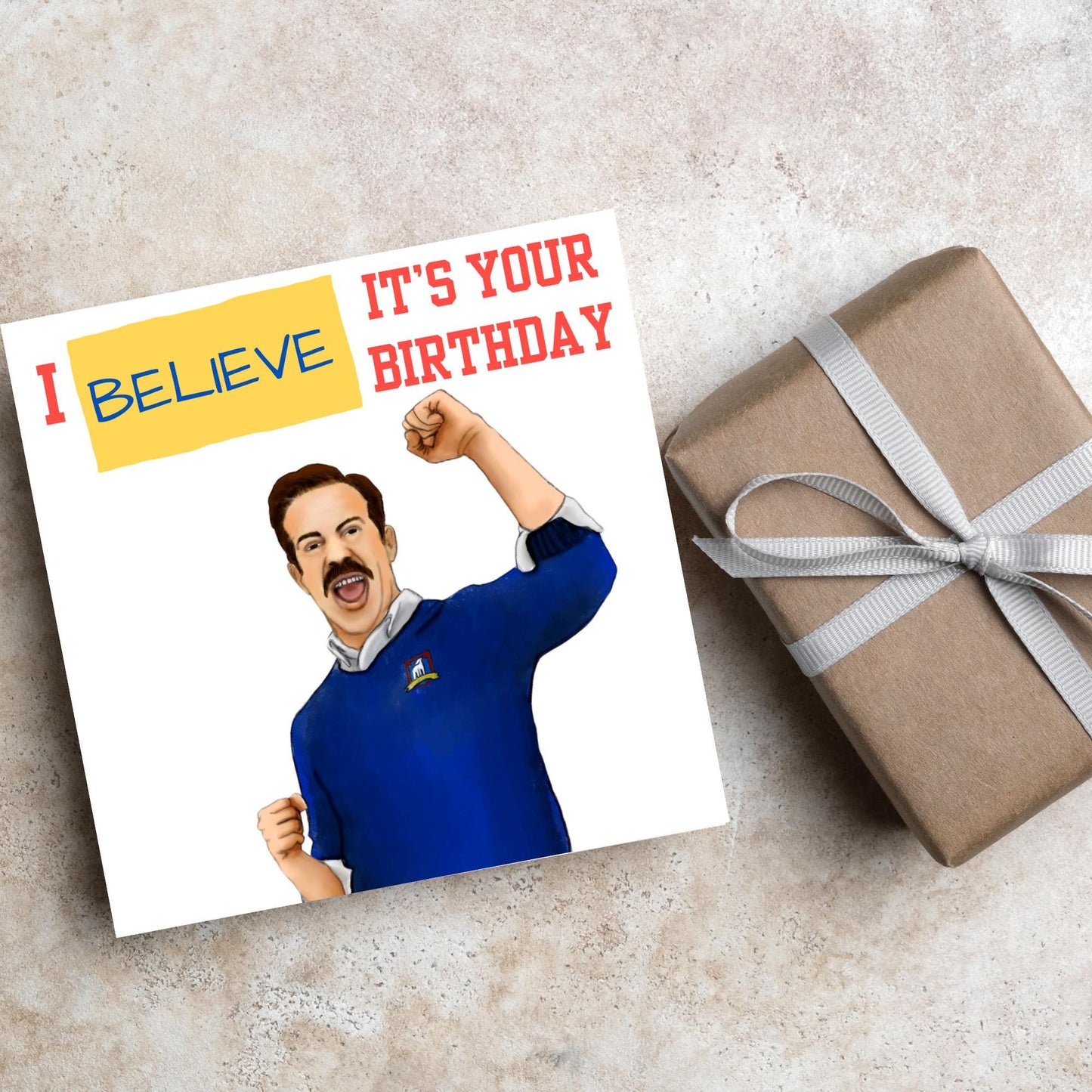 square greetings card with a hand drawn image of Jason Sudeikis character Ted Lasso giving a fist pump with the text - I believe it's your birthday