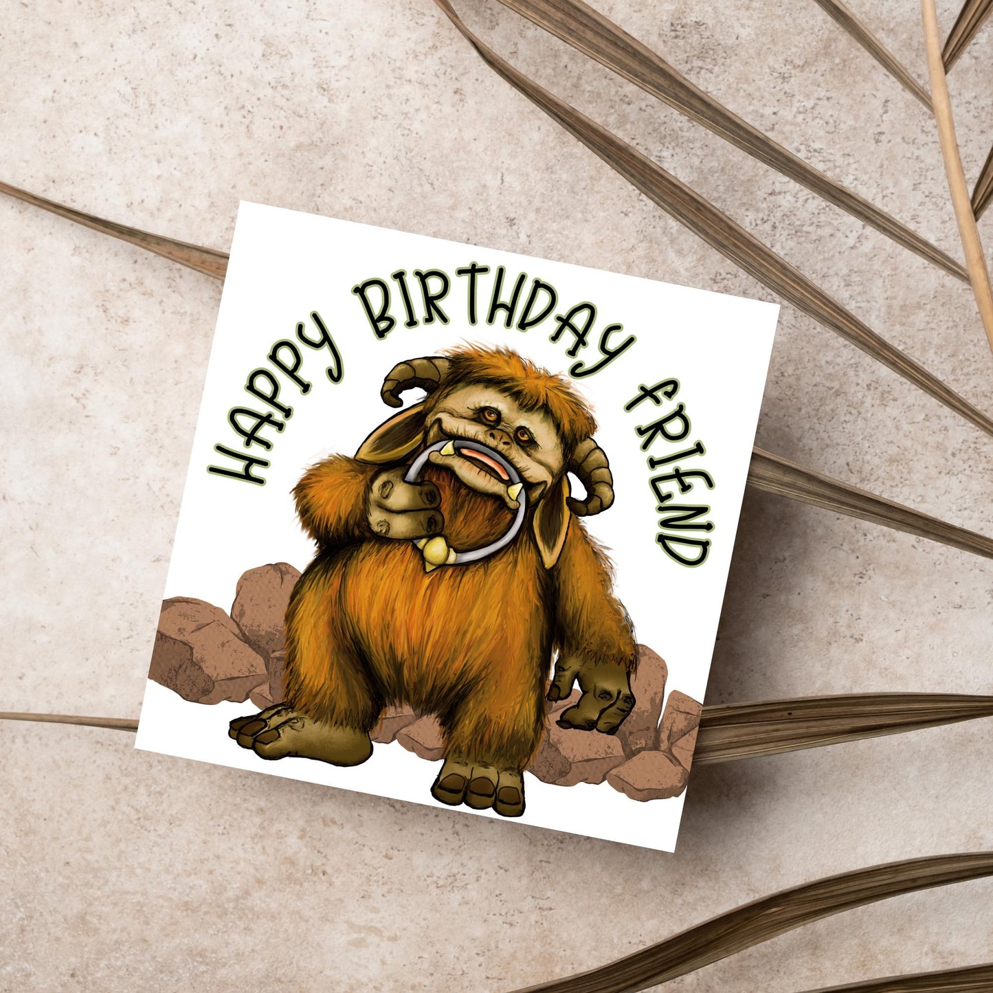 This square shaped card has an illustration of Ludo from the 80s Bowie film Labyrinth. Ludo towers over some rocks and has a door knocker in their mouth. The caption reads Happy Birthday Friend, this text arches above Ludo. This card is perfect for any fans of the film Labyrinth