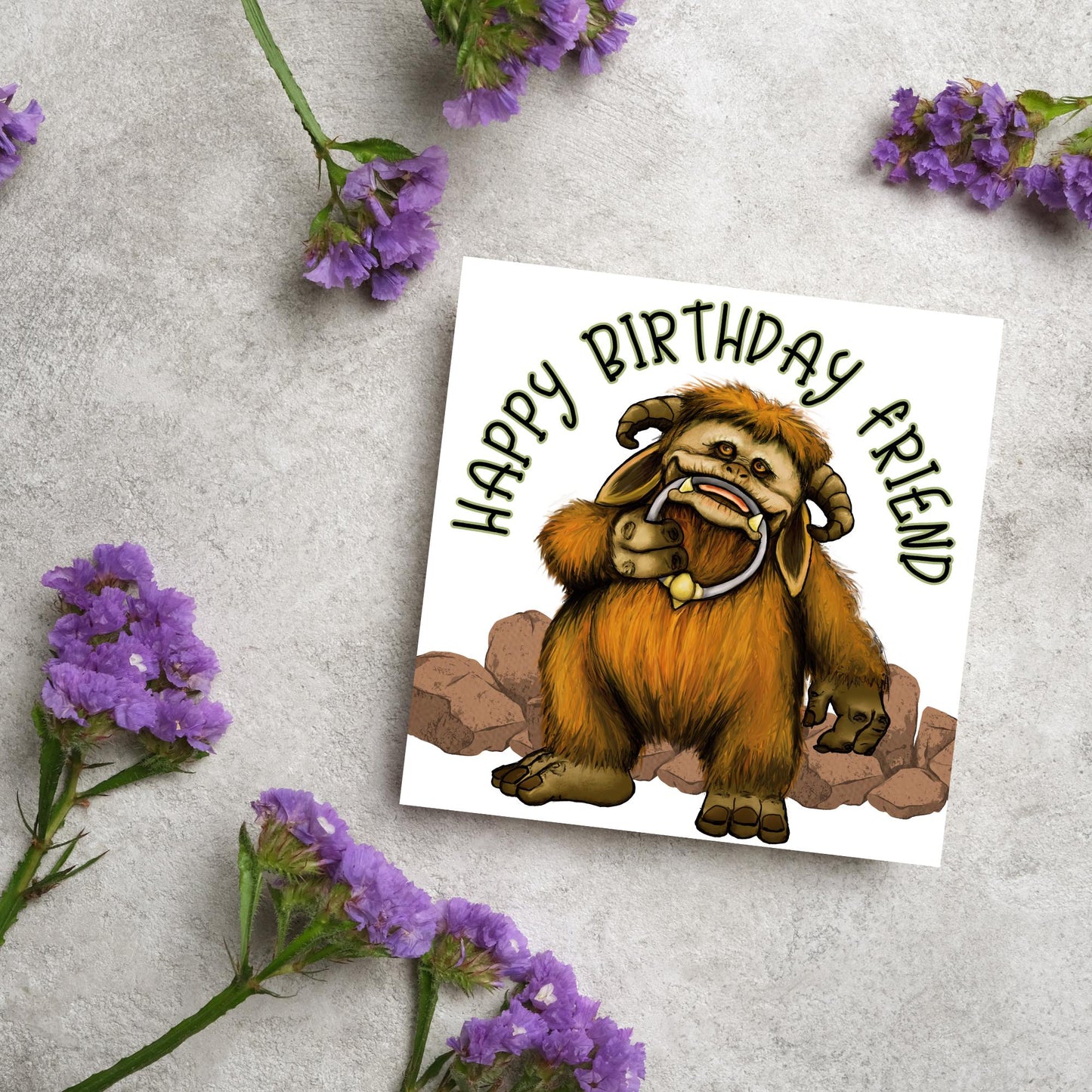 This square shaped card has an illustration of Ludo from the 80s Bowie film Labyrinth. Ludo towers over some rocks and has a door knocker in their mouth. The caption reads Happy Birthday Friend, this text arches above Ludo. This card is perfect for any fans of the film Labyrinth