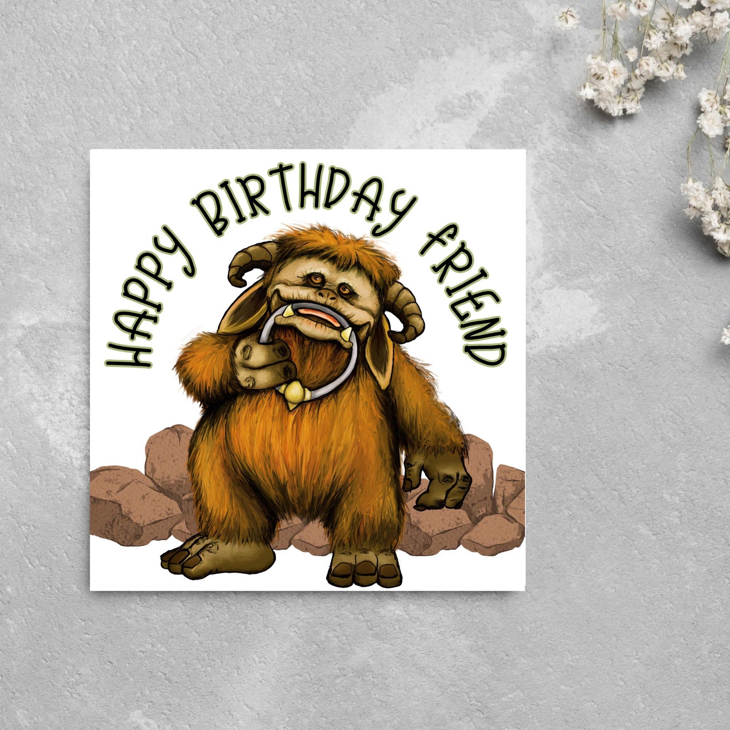 This square shaped card has an illustration of Ludo from the 80s Bowie film Labyrinth. Ludo towers over some rocks and has a door knocker in their mouth. The caption reads Happy Birthday Friend, this text arches above Ludo. This card is perfect for any fans of the film Labyrinth