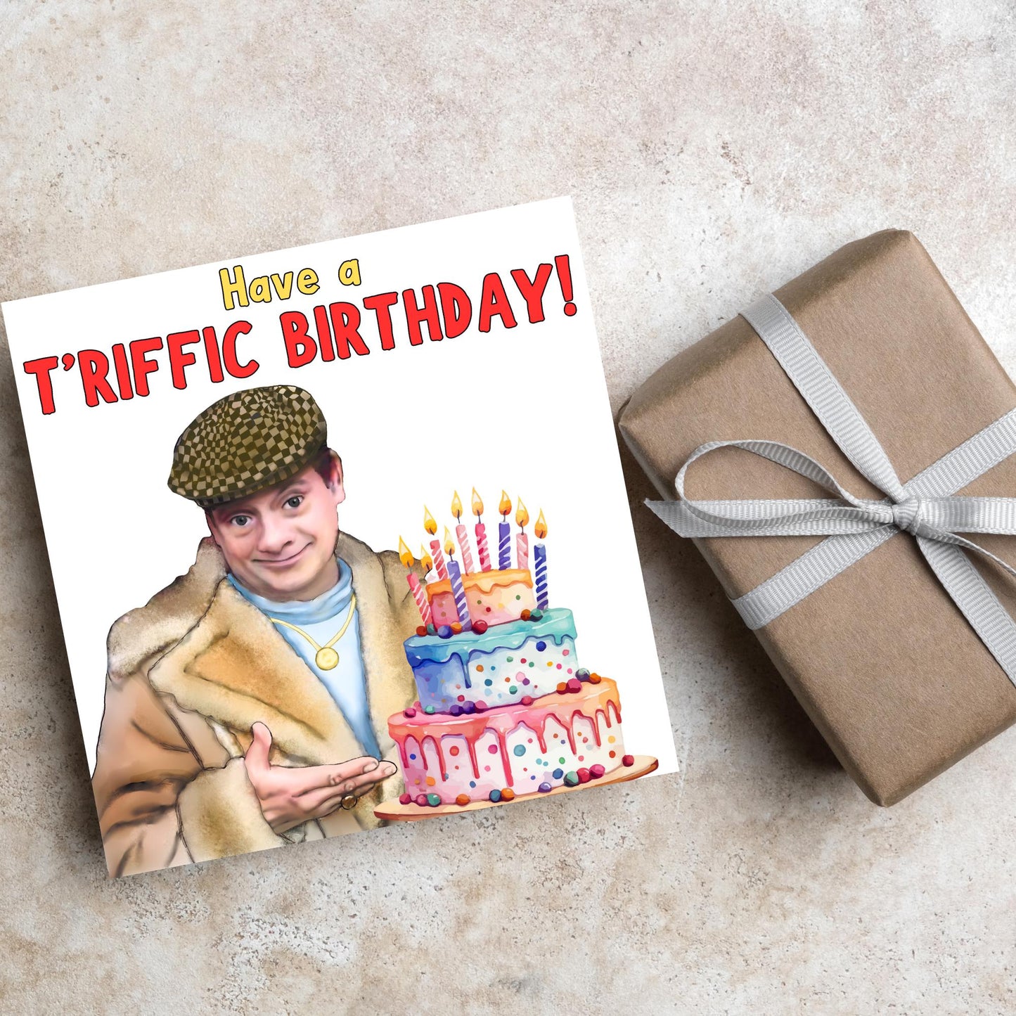 This square shaped card has an illustration of Del Boy from the British Sitcom Only Fools and Horses. The Card has Del Boy standing and pointing at an illustration of a triple tower birthday cake. The Caption reads have a T'riffic Birthday! The Caption is in a mustard yellow and ketchup red