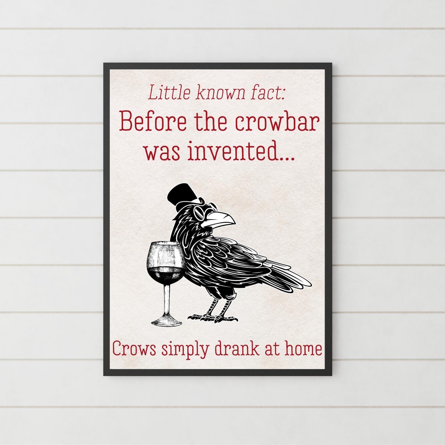 This poster is in an A4 Black bordered frame. Inside of the framed art print poster is an illustration of a crow, with round sunglasses and a top-hat in a black and white monochrome design. Beside the crow is a wine glass. The caption on the poster reads "Little Known Fact: Before the crowbar was invented crows simply drank at home" This poster is perfect for any crow enthusiasts