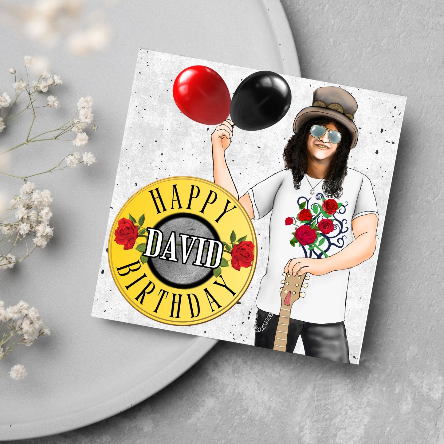 Square Birthday card with an illustration of Slash from Guns and Roses holding a red balloon and a black balloon in one hand, and resting his other on his guitar. He is wearing his trademark top hat, a rose print tee shirt and sunglasses. There is a band style logo that reads happy birthday david to the left of him.