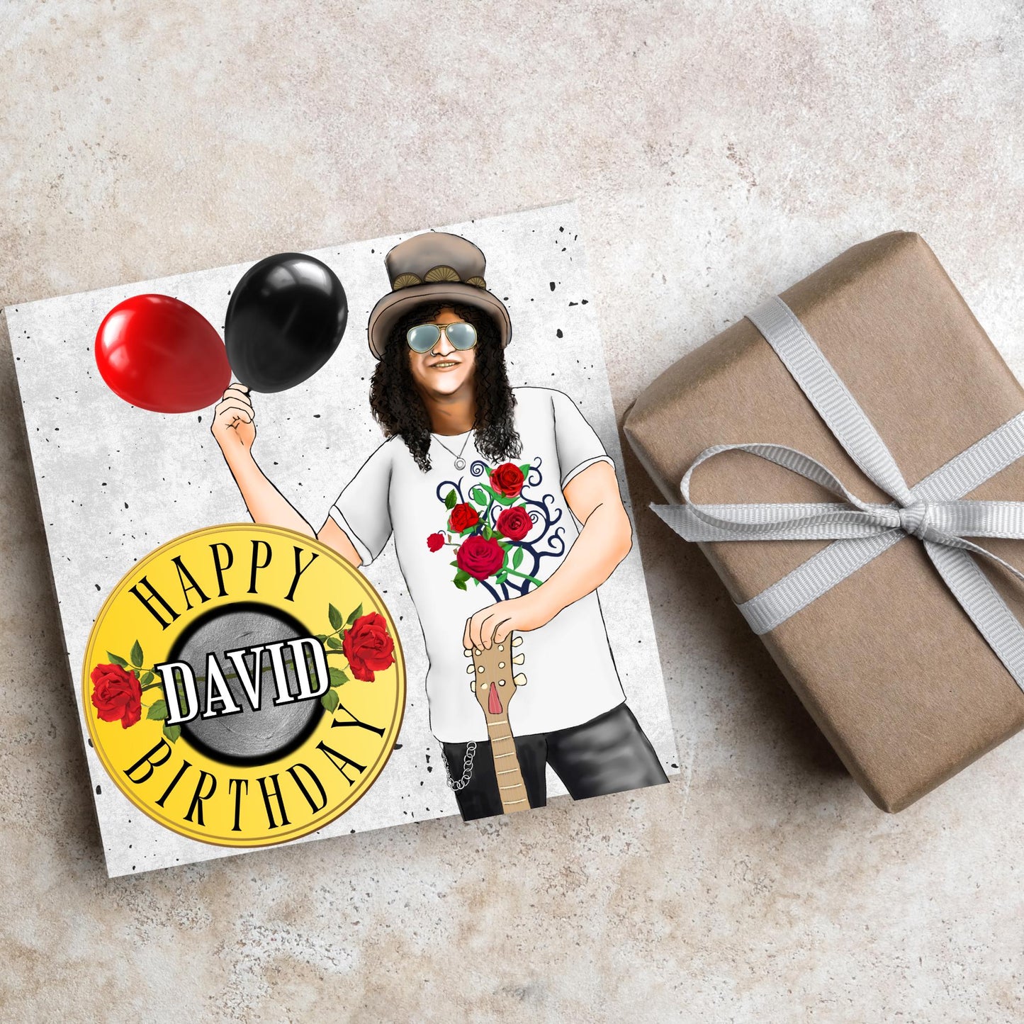 Square Birthday card with an illustration of Slash from Guns and Roses holding a red balloon and a black balloon in one hand, and resting his other on his guitar. He is wearing his trademark top hat, a rose print tee shirt and sunglasses. There is a band style logo that reads happy birthday david to the left of him.