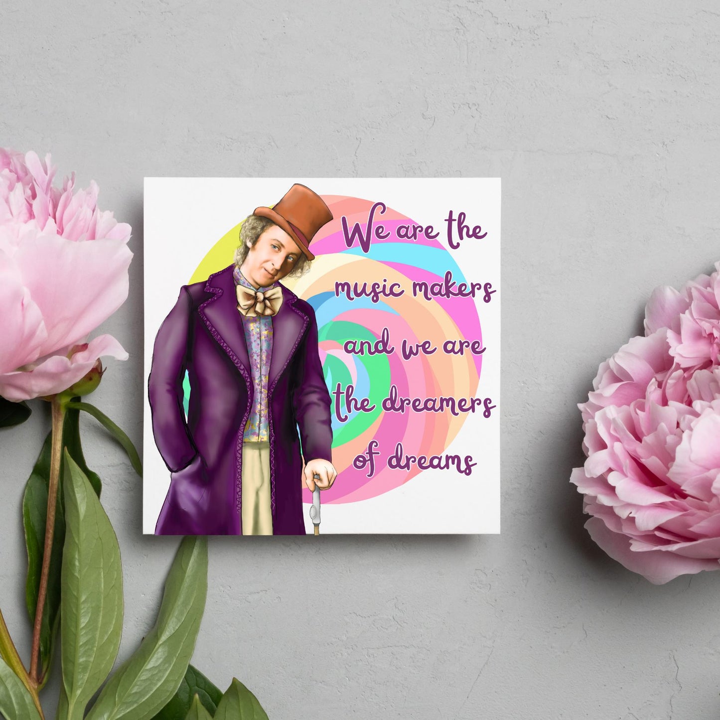 Image of a square greeting card. The background of the card is white and there is a hand drawn image of Gene Wilder as Willy Wonka wearing his purple coat, top hat and bow tie. Behind him is a colourful swirly lollypop and purple text reads 'we are the music makers and we are the dreamers of dreams' in a curly font.