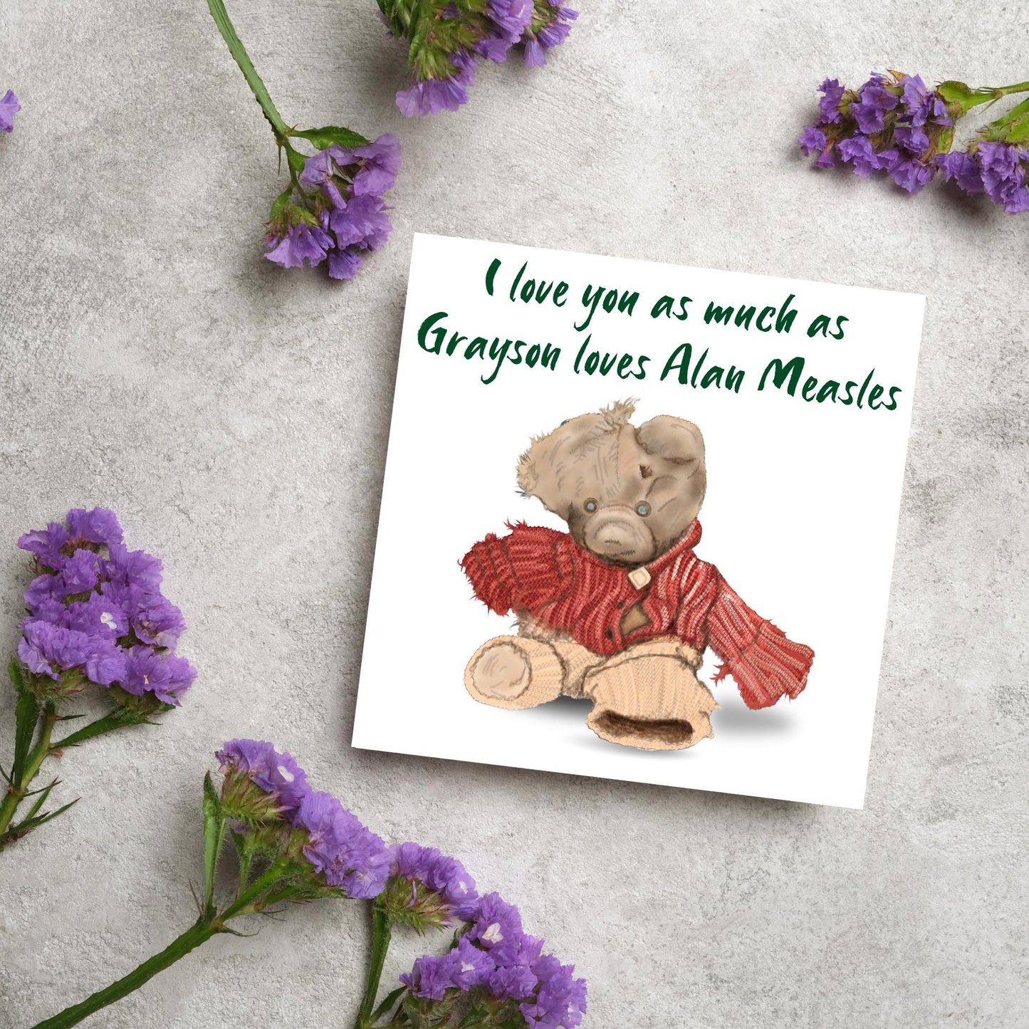 This is an image of a square anniversary card with a hand drawn illustration of Grayson Perry's beloved Alan Measels teddy bear with hand written style that says 'I love you as much as Grayson loves Alan Measels'.
