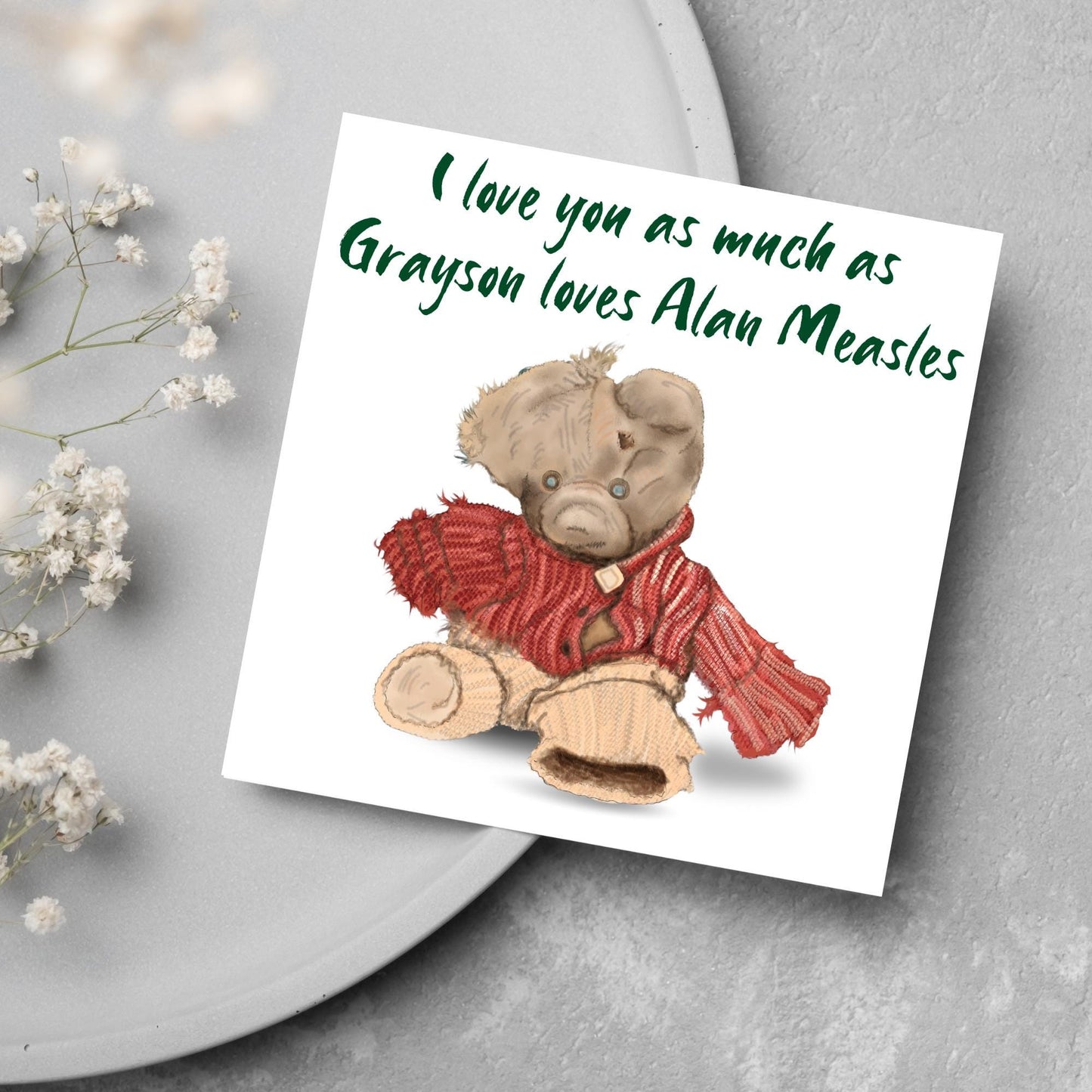 This is an image of a square anniversary card with a hand drawn illustration of Grayson Perry's beloved Alan Measels teddy bear with hand written style that says 'I love you as much as Grayson loves Alan Measels'.