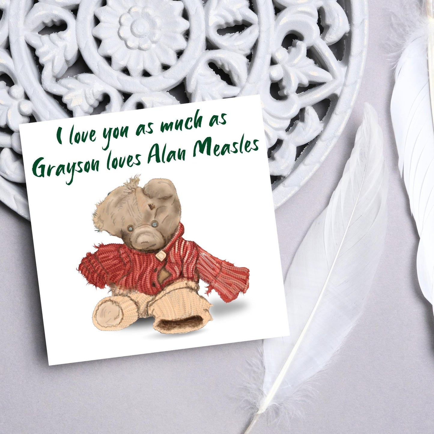 This is an image of a square anniversary card with a hand drawn illustration of Grayson Perry's beloved Alan Measels teddy bear with hand written style that says 'I love you as much as Grayson loves Alan Measels'.