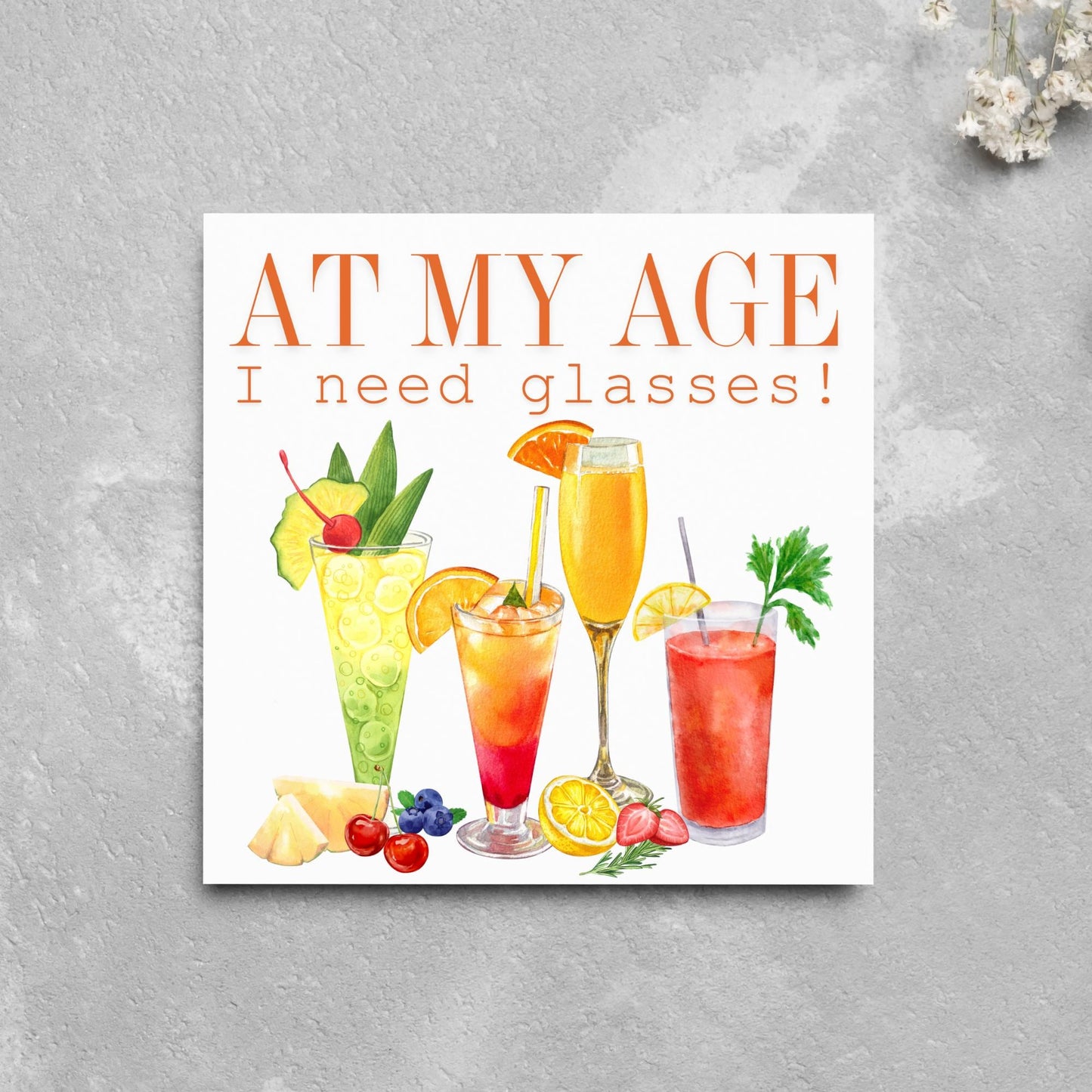 Image of a square birthday card with colourful illustrations of cocktails with the text - at my age I need glasses!
