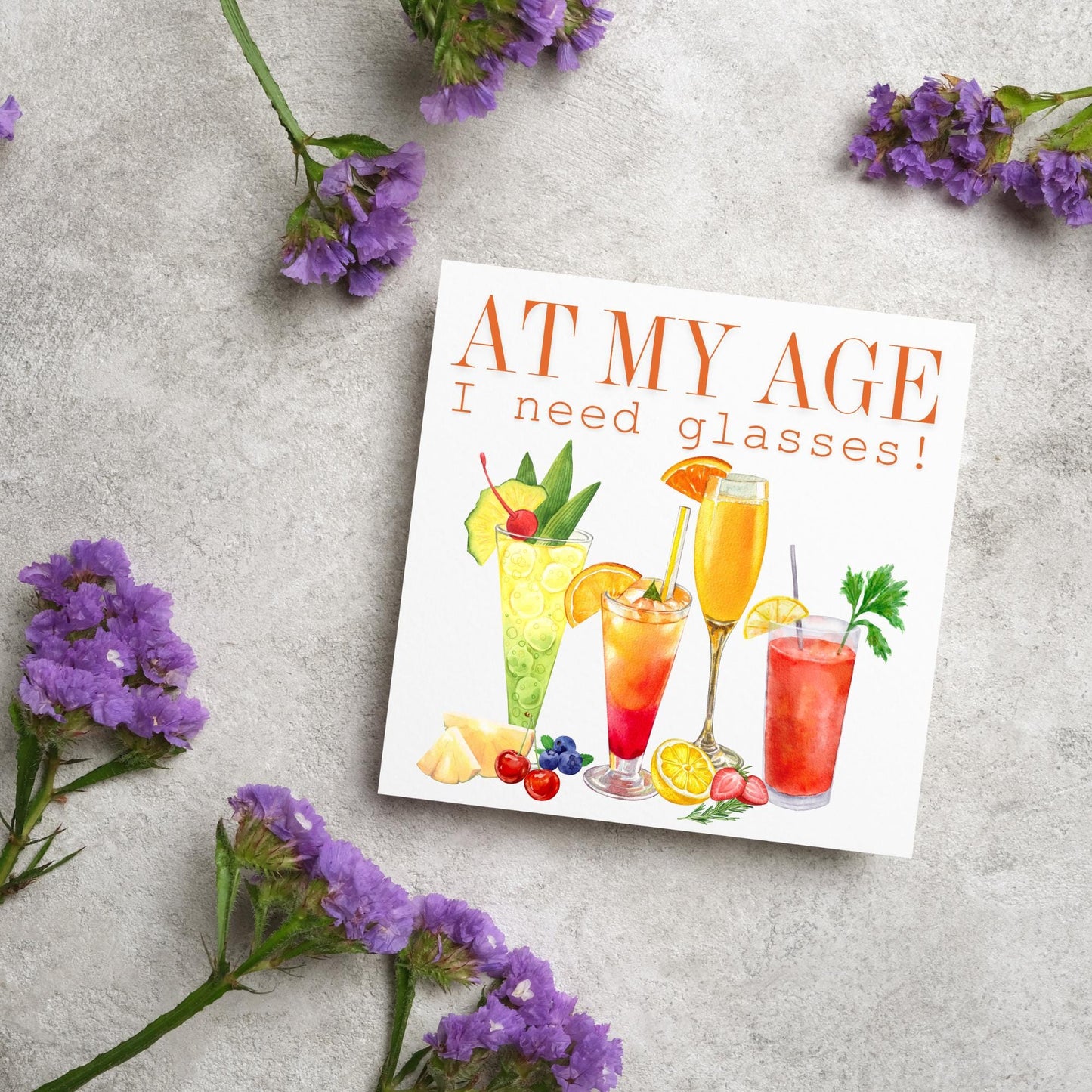 Image of a square birthday card with colourful illustrations of cocktails with the text - at my age I need glasses!