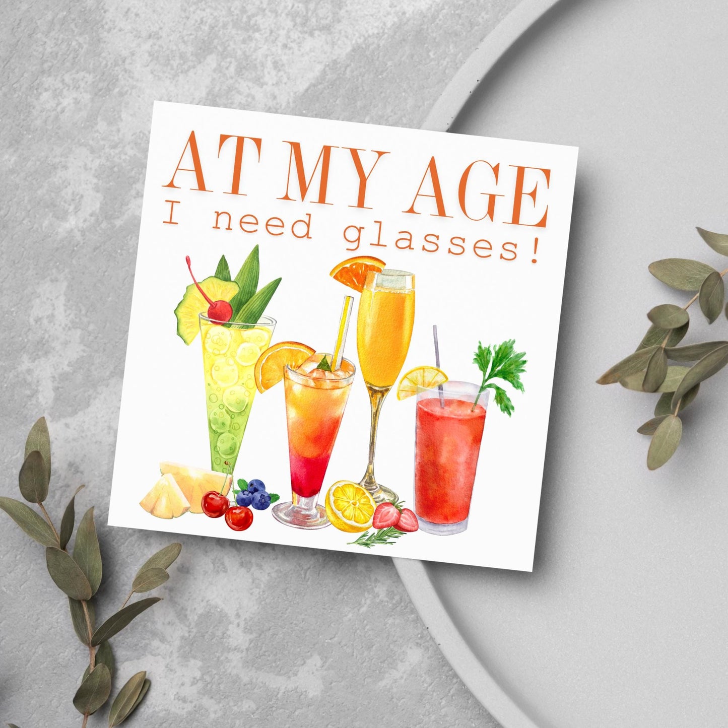 Image of a square birthday card with colourful illustrations of cocktails with the text - at my age I need glasses!