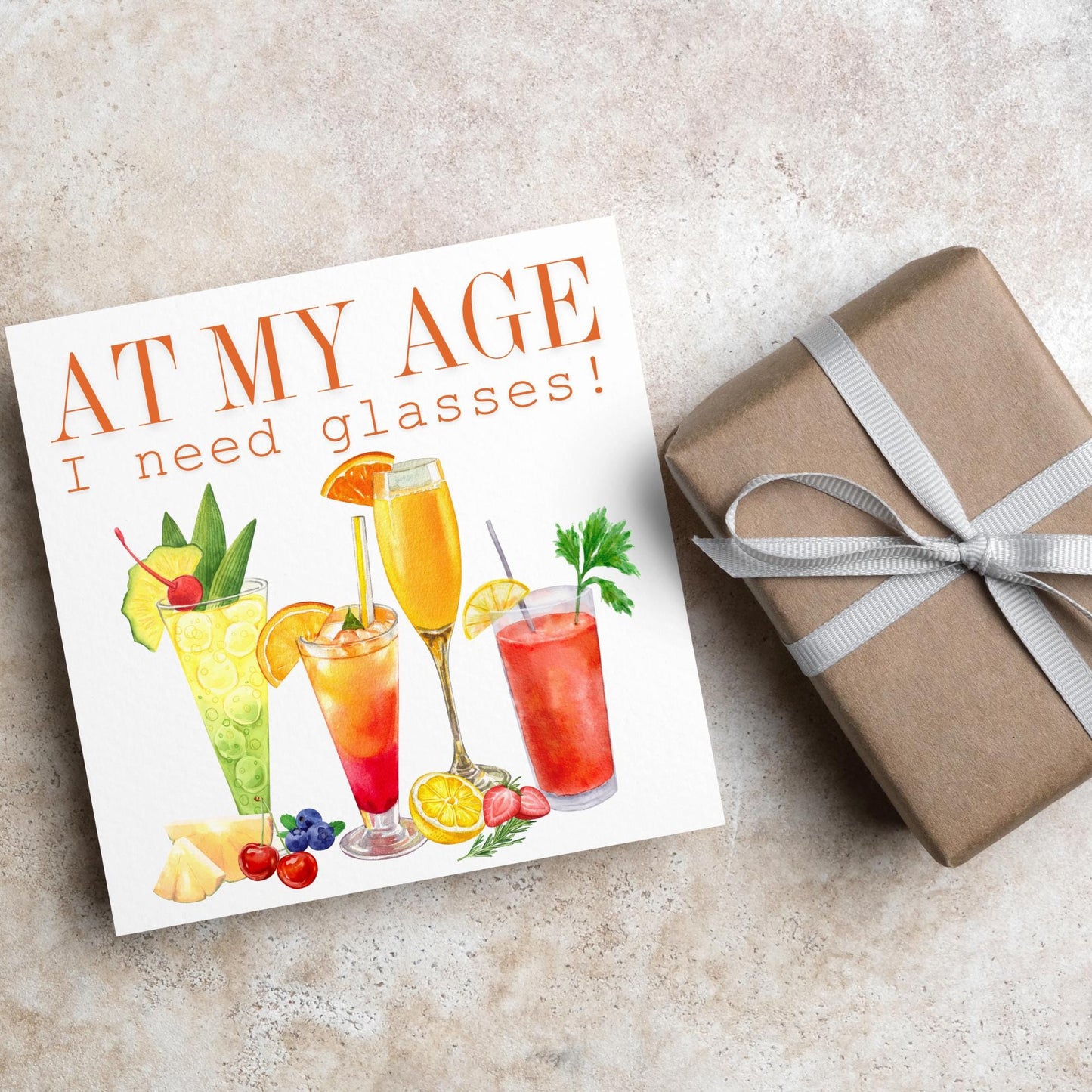 Image of a square birthday card with colourful illustrations of cocktails with the text - at my age I need glasses!