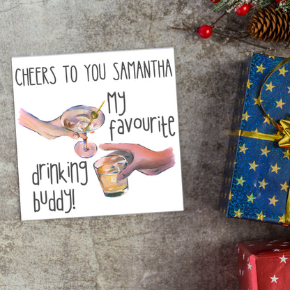Square card with watercolour design of 2 hands holding drinks glasses against a white background, with grey text that reads &quot;cheers to you Samantha, my favourite drinking buddy&quot;