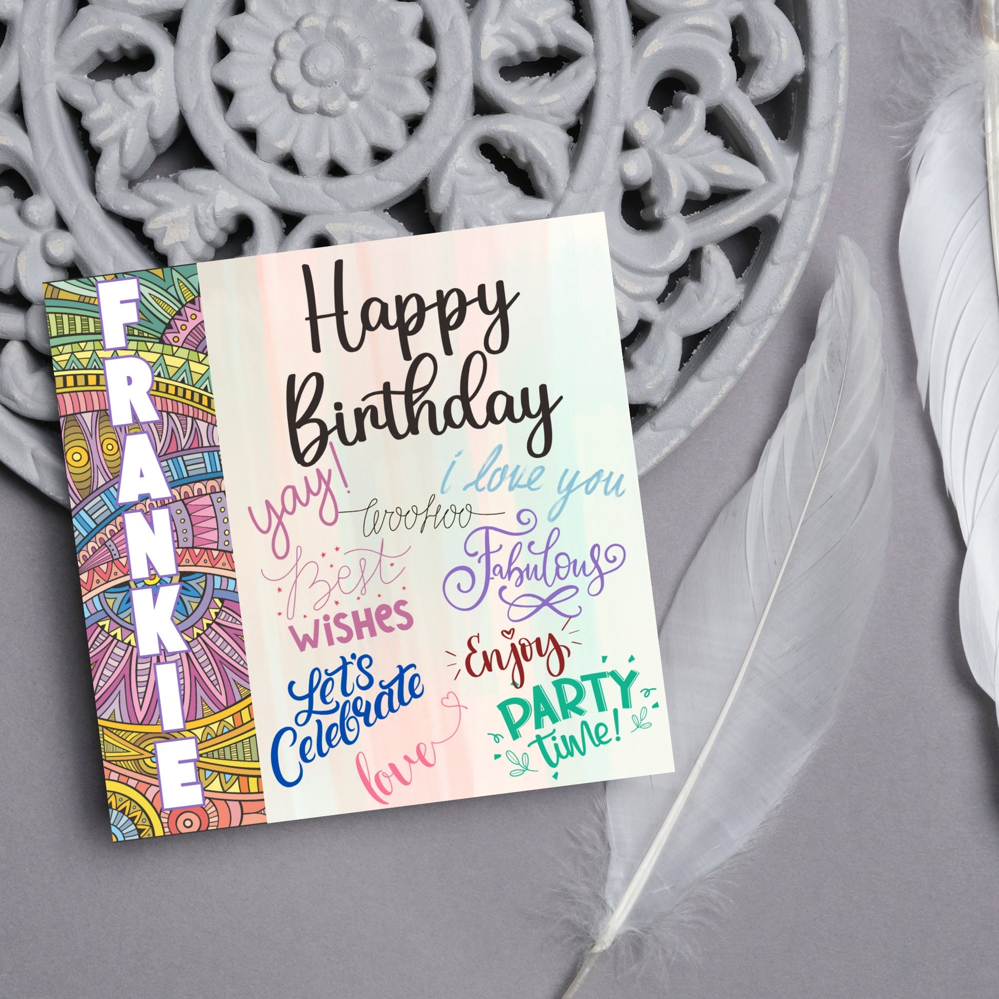 Square birthday card with bold patterned edge with the recipients name overlaid in white. the rest of the card says happy birthday over a pastel background, with messages of yay, I love you, woohoo, best wishes, lets celebrate, enjoy, party time